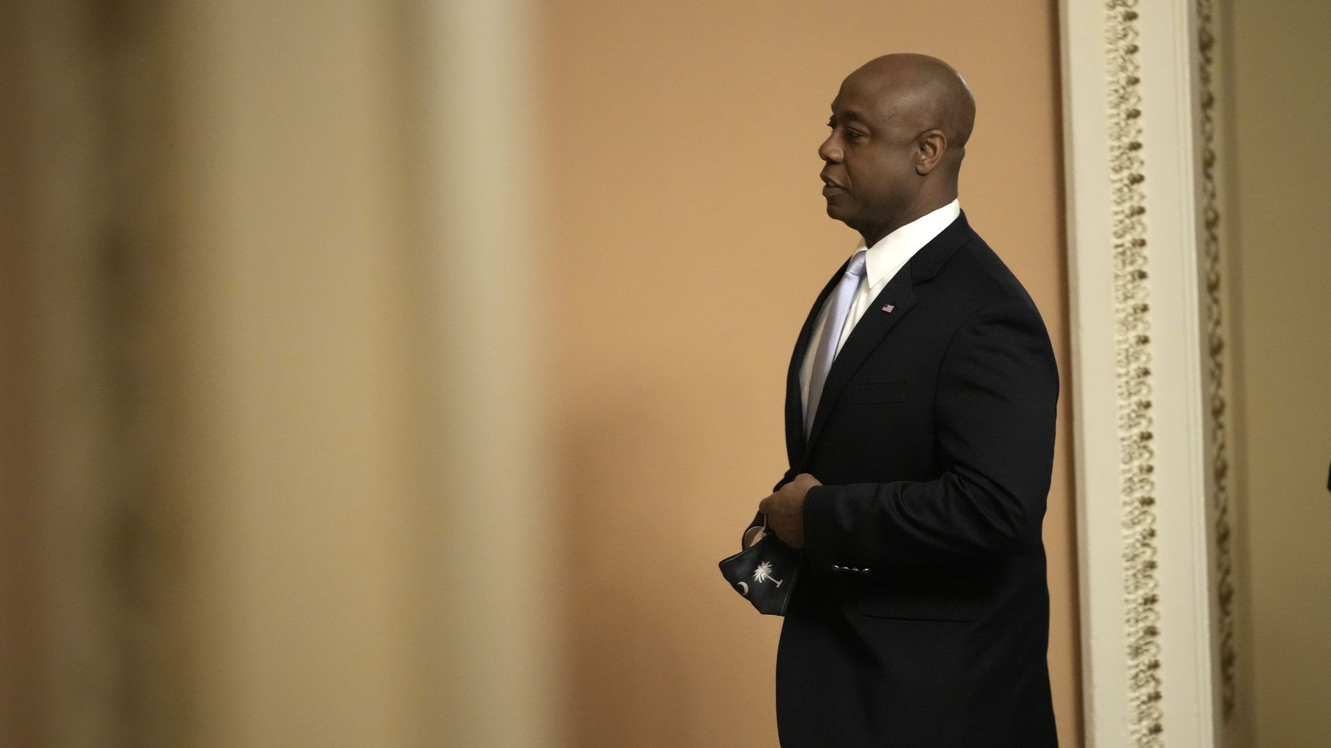 Photo of Tim Scott holding a mask and walking