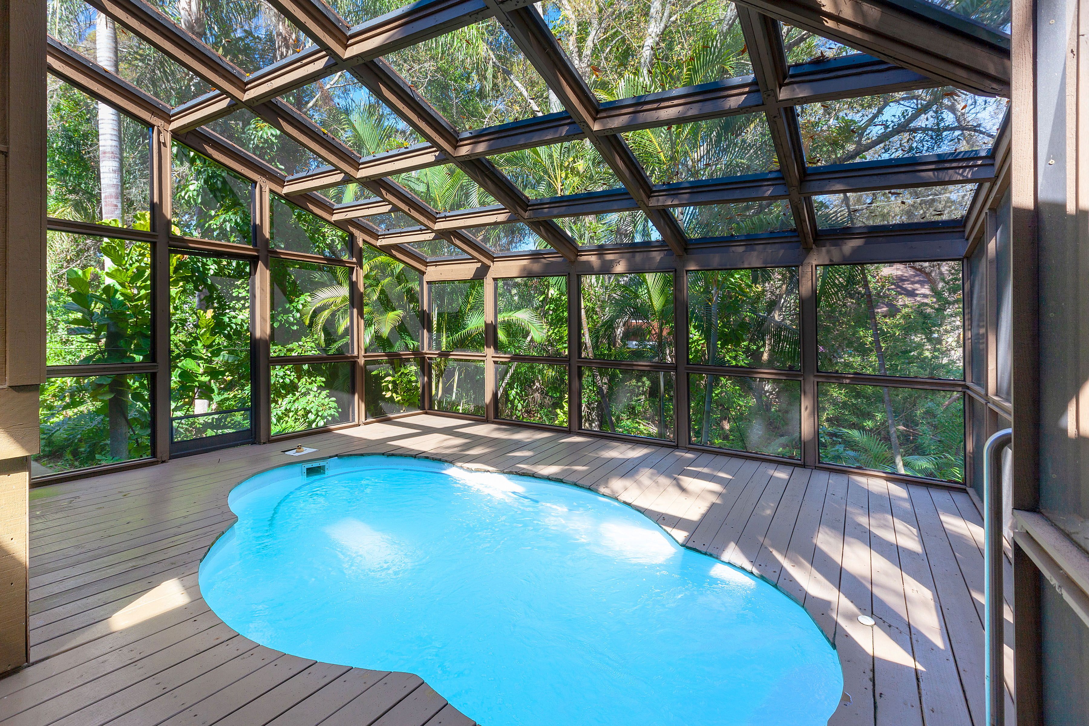 A screened-in pool surrounded by lush greenery 