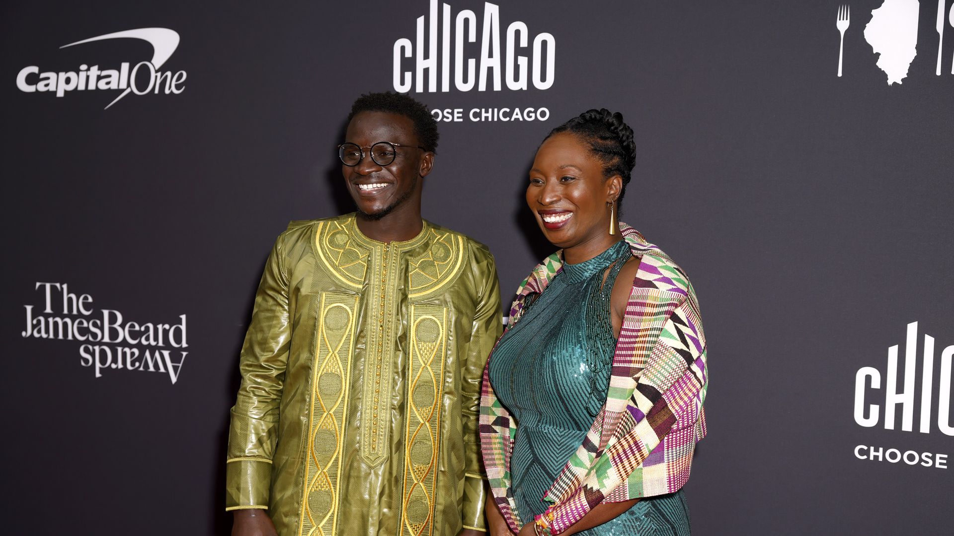 Chef Serigne Mbaye poses on the red carpet with his date, both wearing bright colors.
