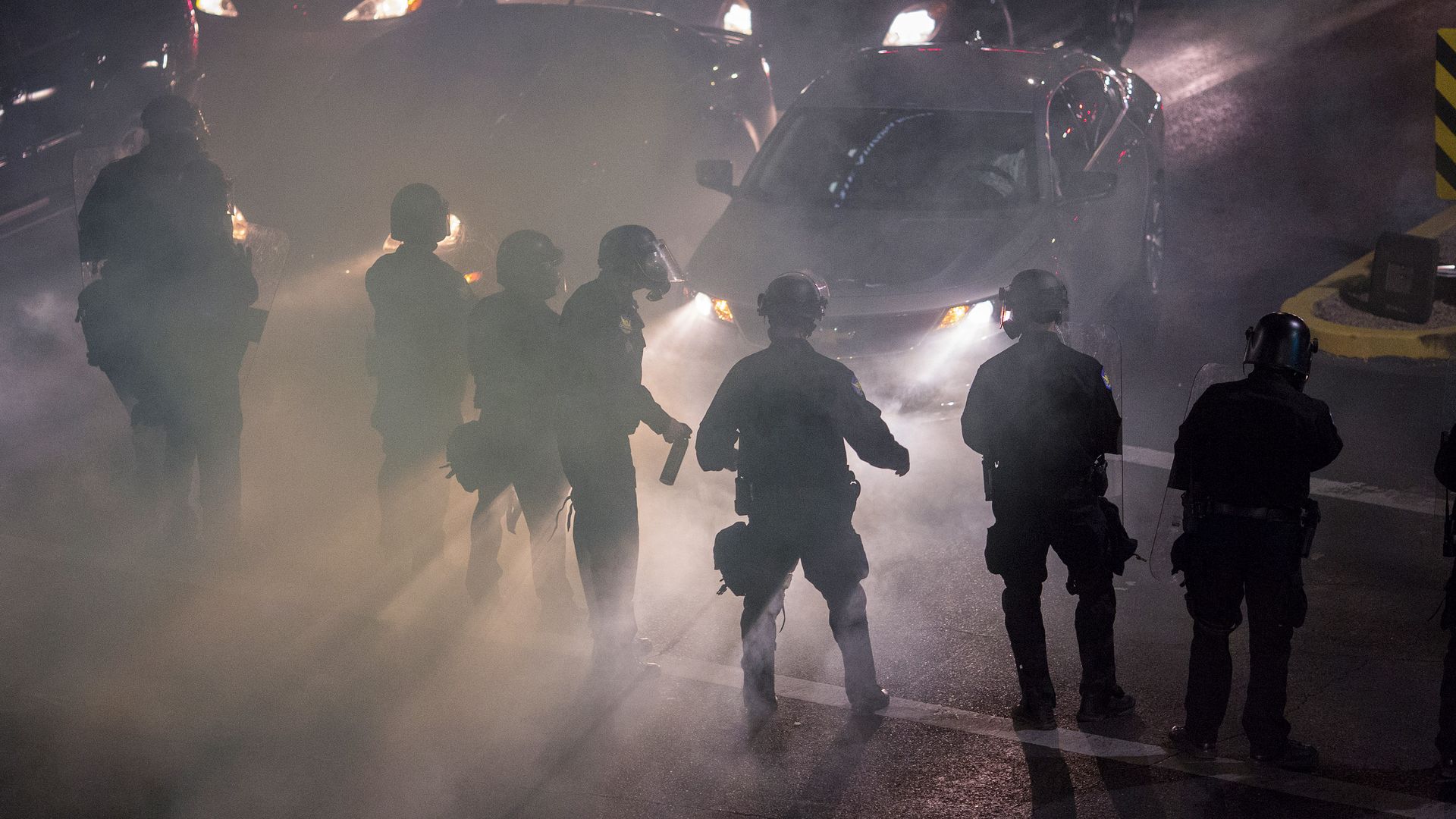 Smoke and tear gas fills the air around trapped drivers as police advance upon demonstrators after a rally by President Donald Trump at the Phoenix Convention Center.