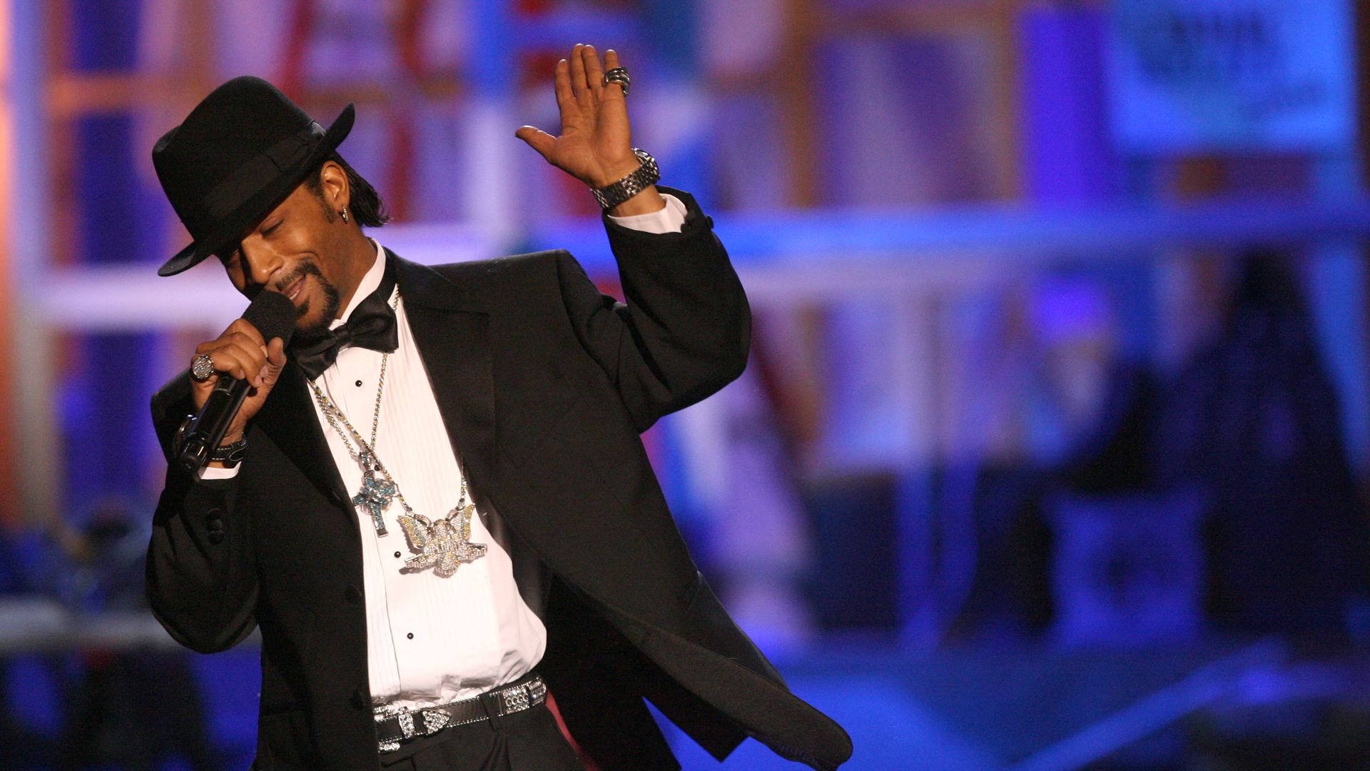 Comedian Katt Williams performs on stage in a tuxedo and top hat. 