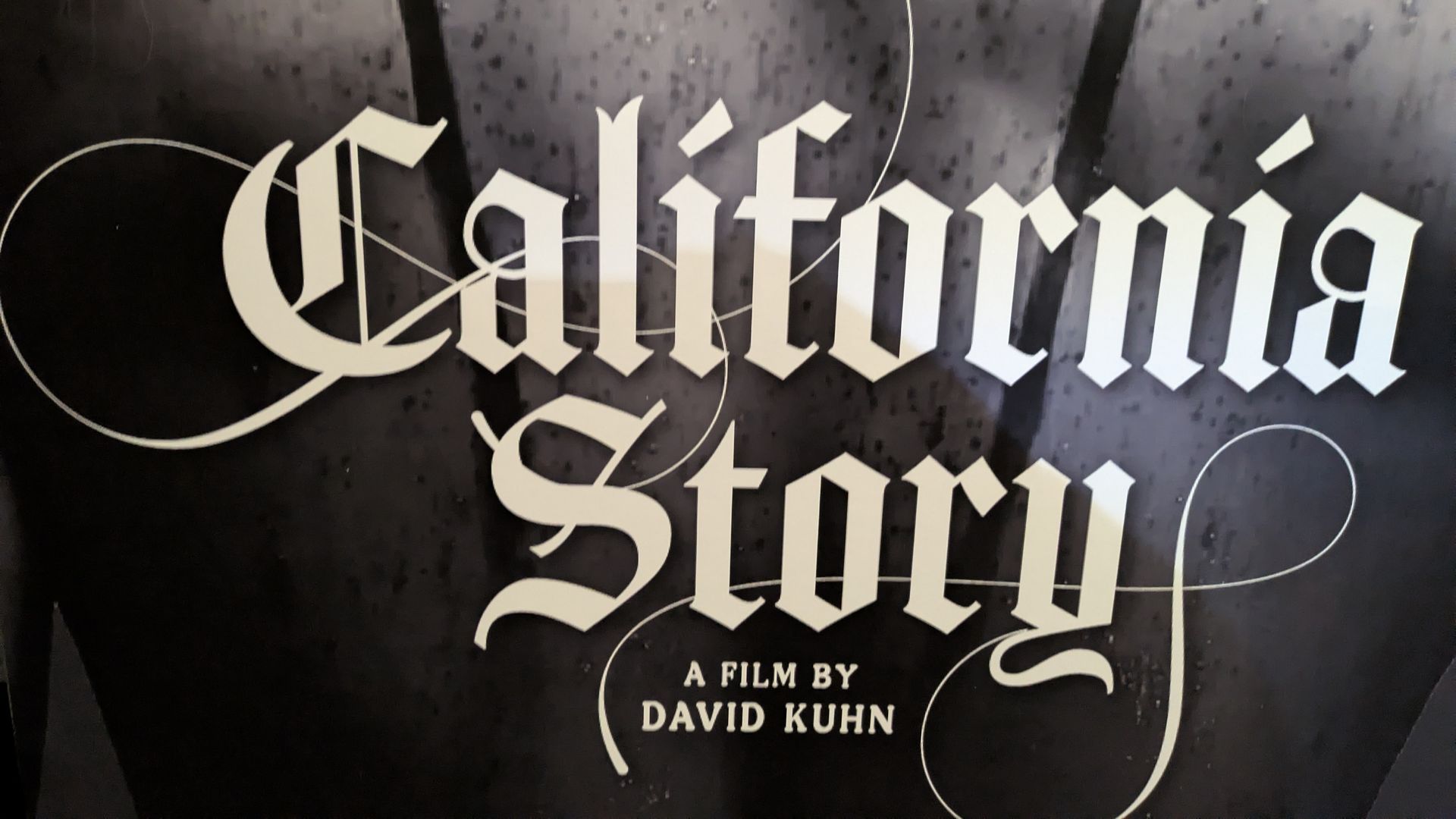 Black and white film poster with gothic font saying "California Story" and smaller text "A film by David Kuhn", with palm trees faintly visible in the background.