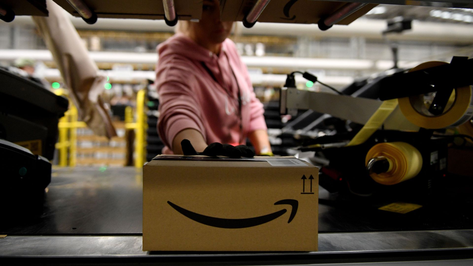 In this image, an Amazon worker reaches for an Amazon package