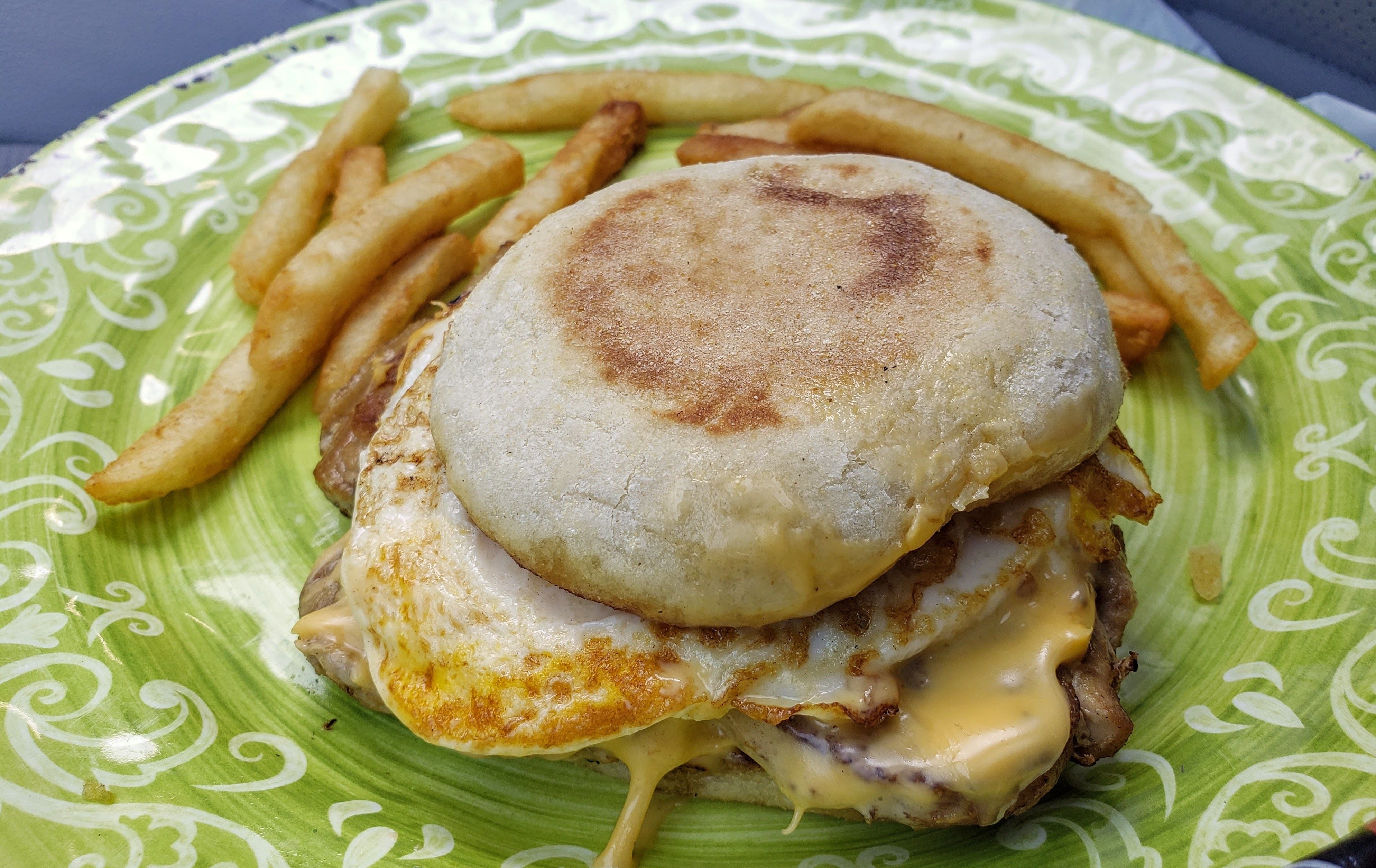 English muffin with egg and cheese and french fries on the side.