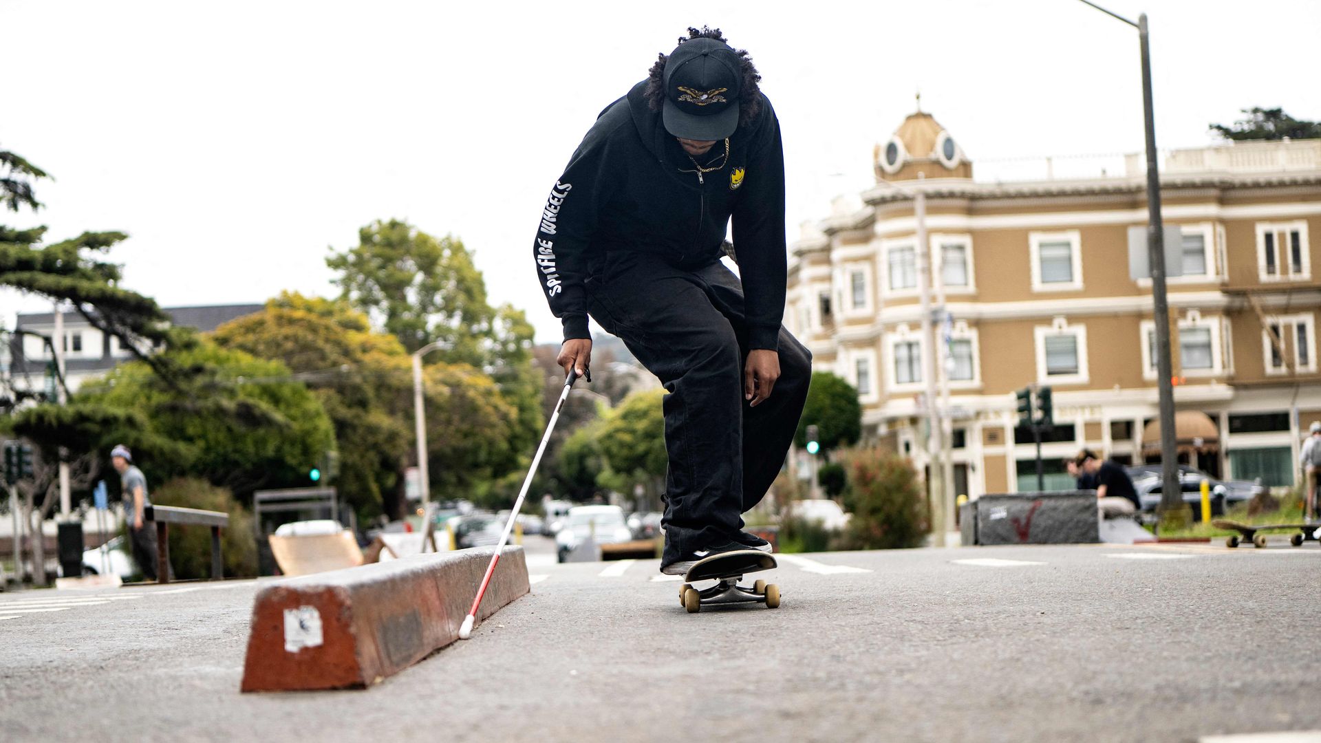 Photo of Zion Williams-Gaines using a cane as he skateboards