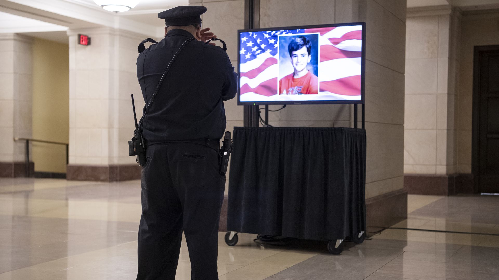 A Capitol police officer covers his face while watching a TV display Brian Sicknick