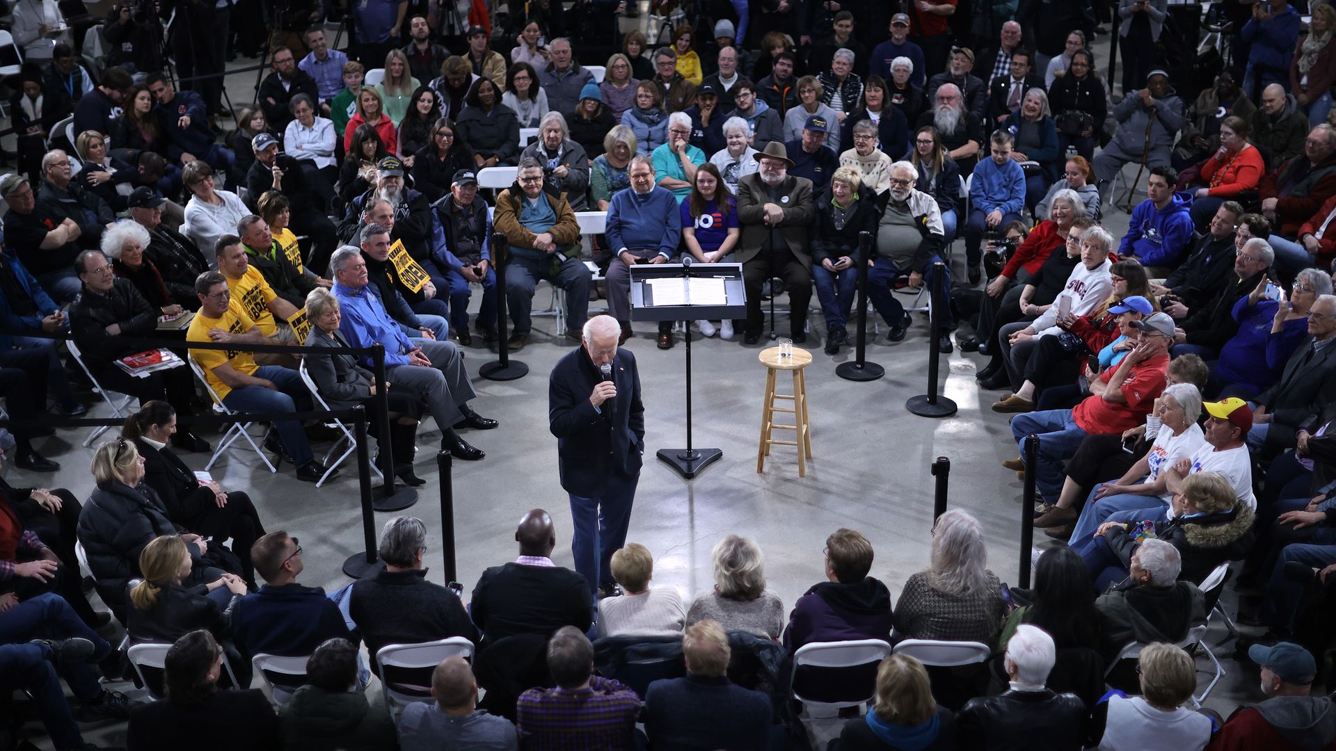 In this image, Bernie Sanders stands in the middle of a circle of spectators at a 2020 campaign event