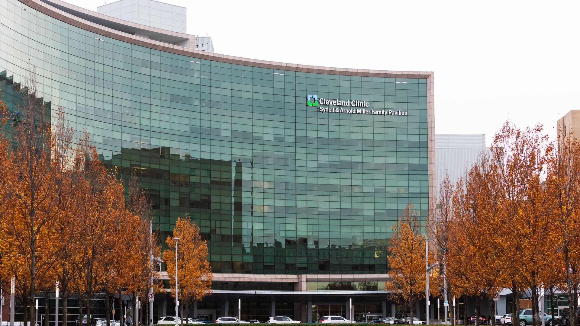 The green Cleveland Clinic hospital building with fall trees nearby.