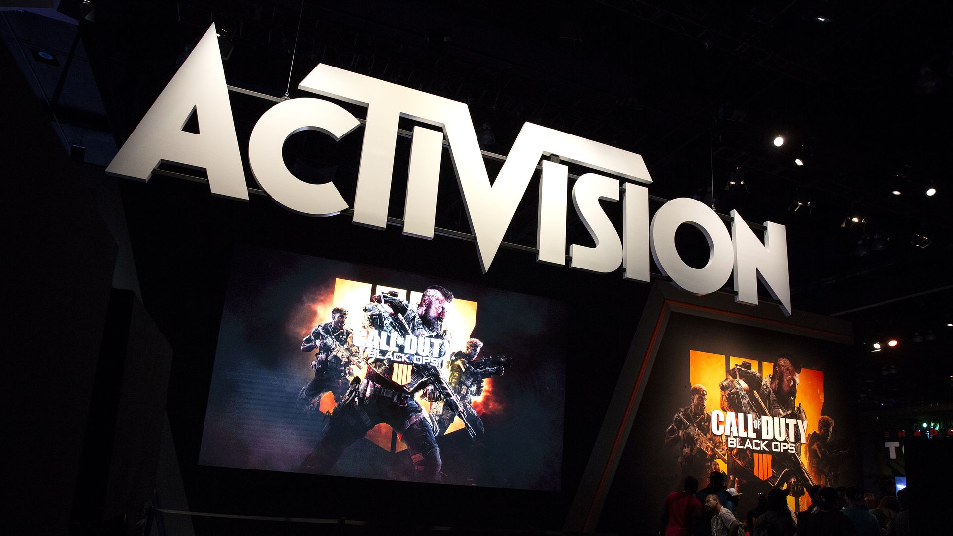 Photo inside a darkened theater where the Activision logo hangs above signage for a Call of Duty war game
