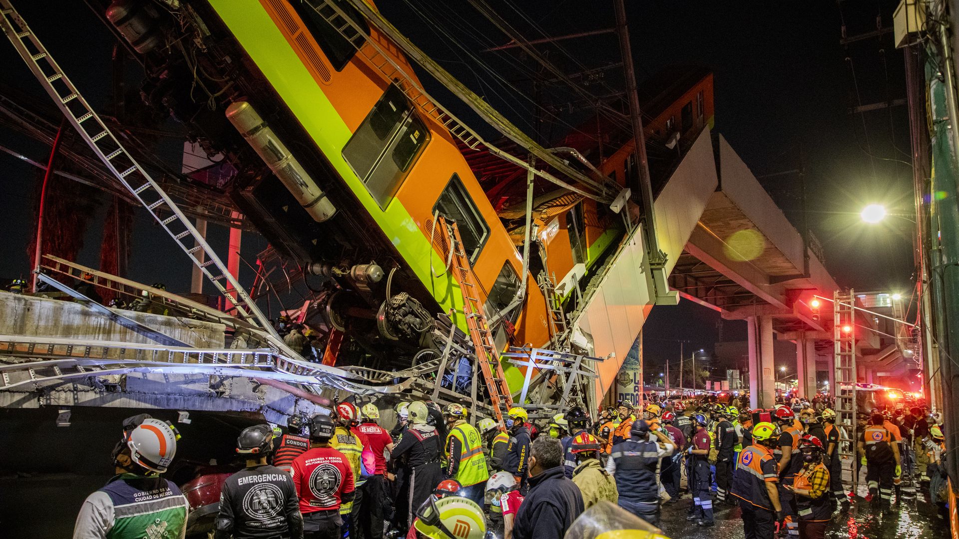 Aid workers and rescuers stand in front of rubble after a section of a bridge on metro line 12 collapsed in Mexico City