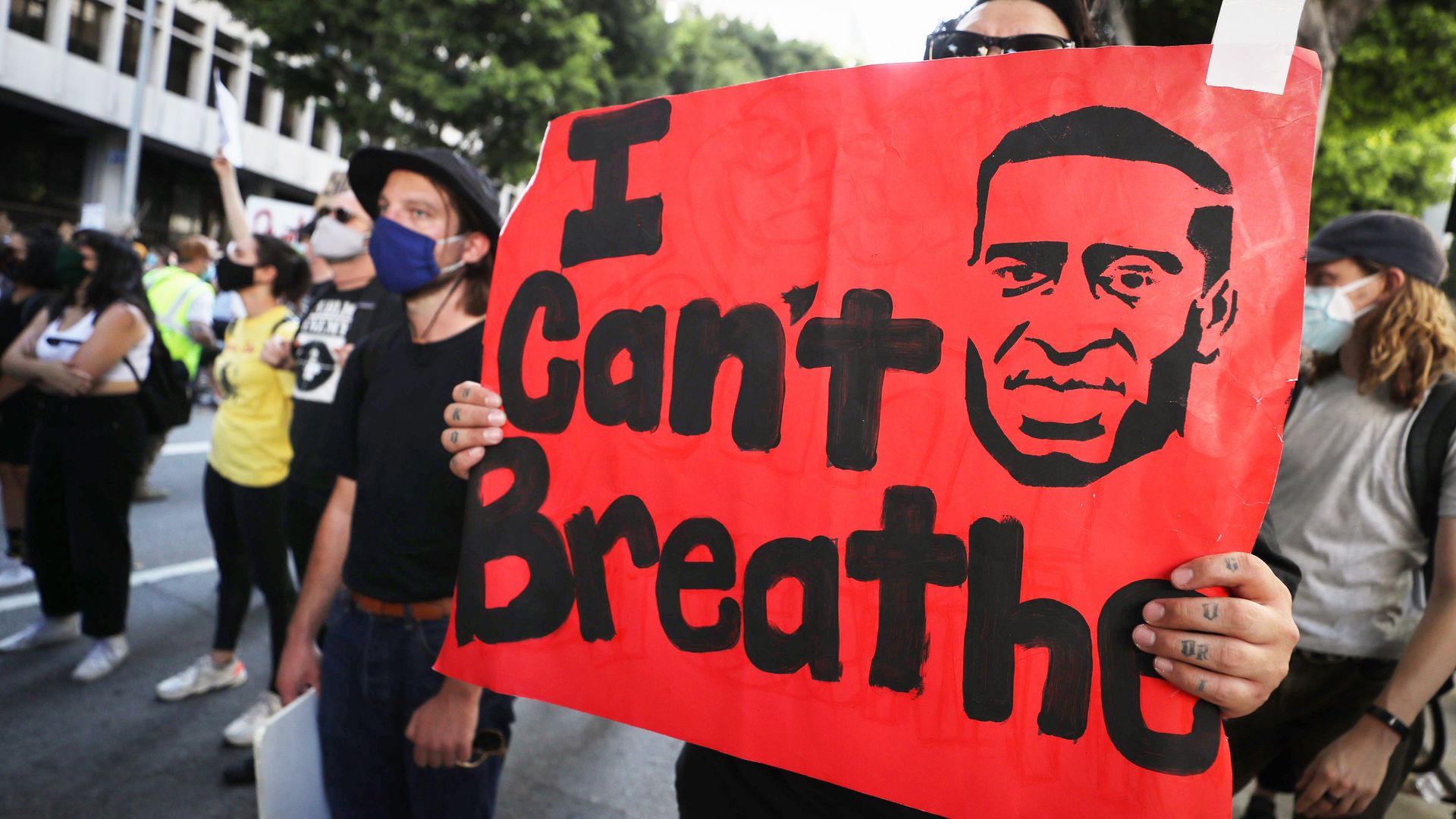 Photo of a person holding a sign that shows a depiction of George Floyd's face and the words "I can't breathe"
