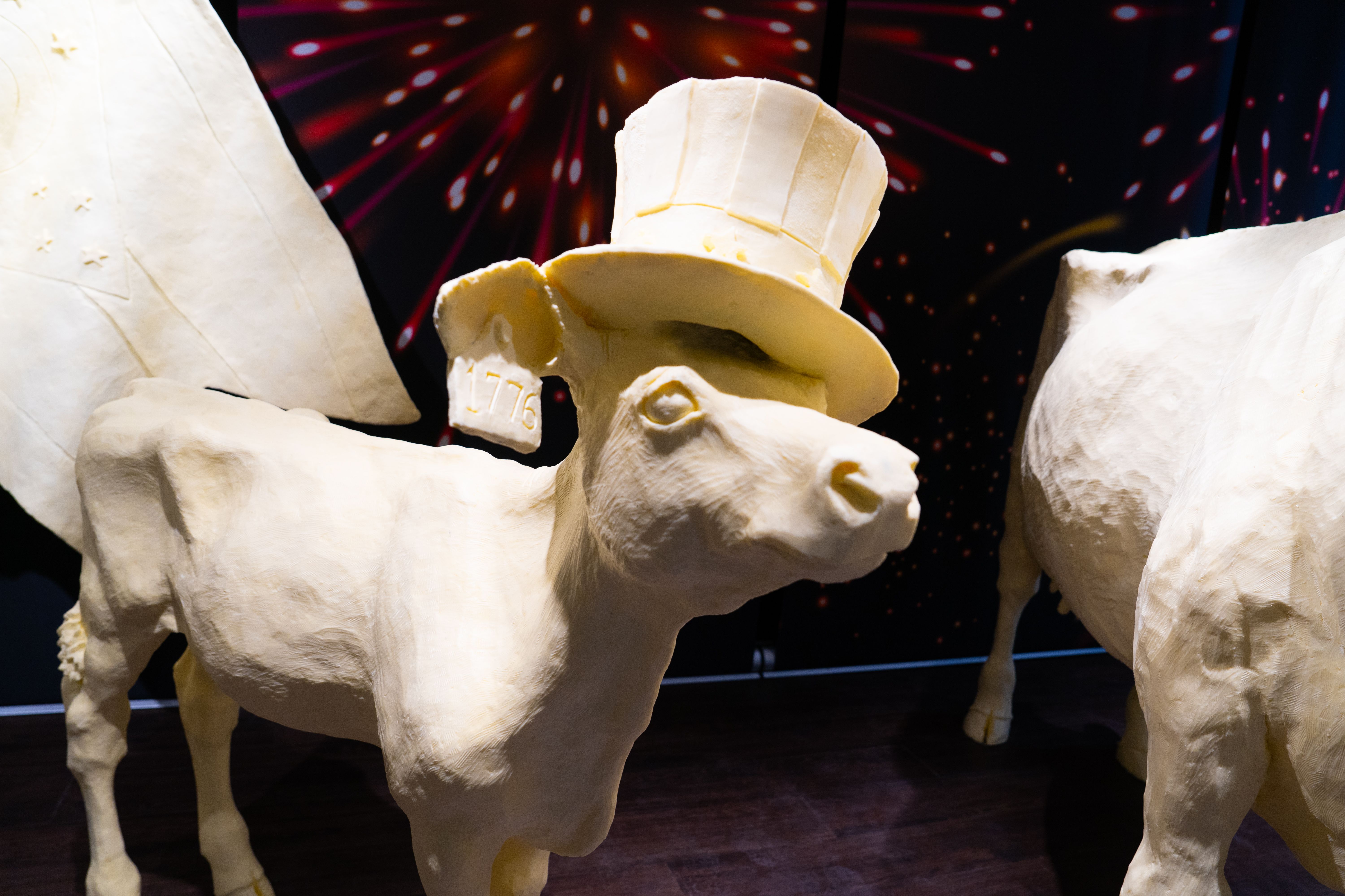A close-up of the butter cow, with a "1776" tag in its ear and wearing a stars and stripes top hat.