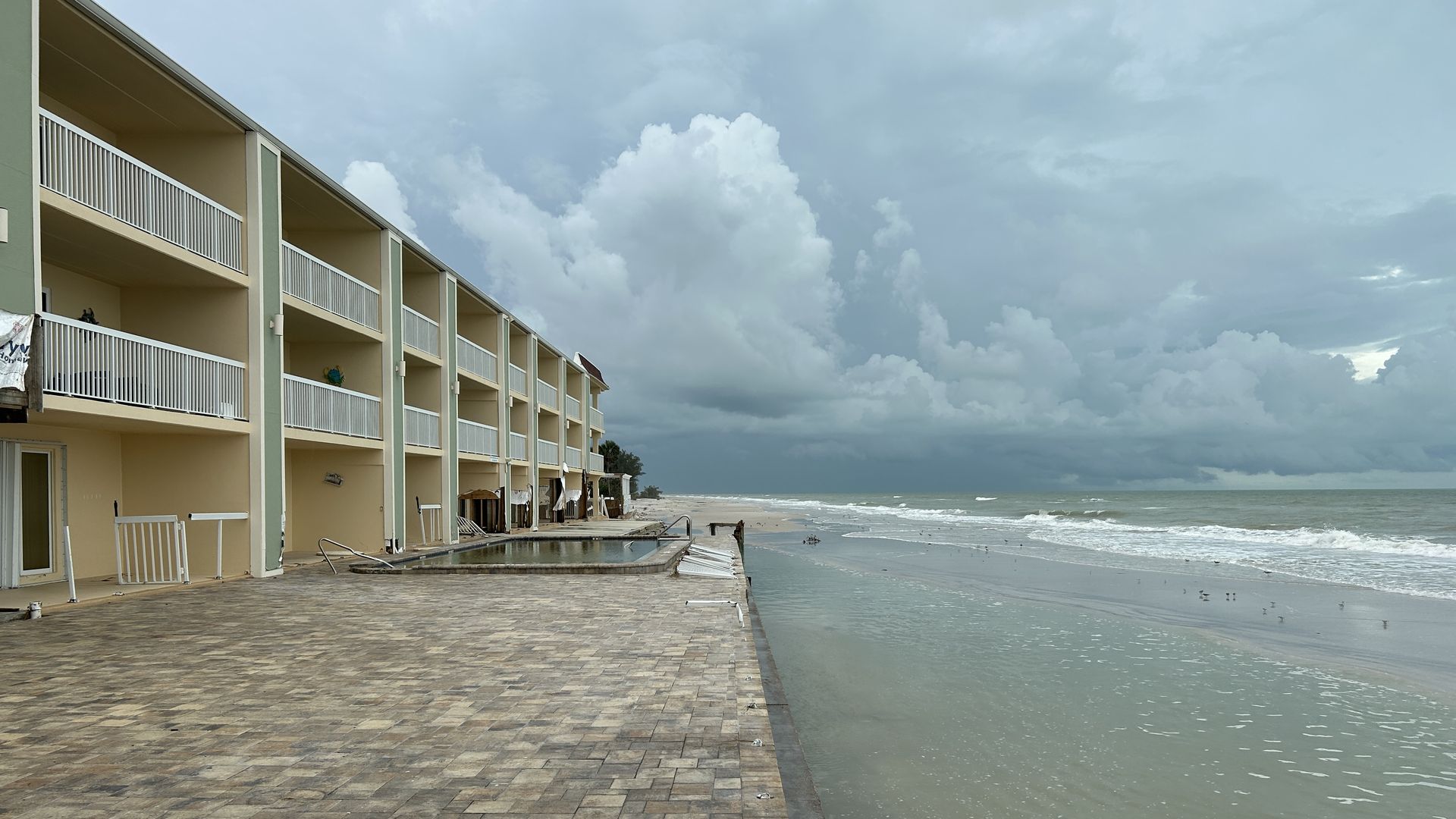 A building with a patio and pool abutting water.