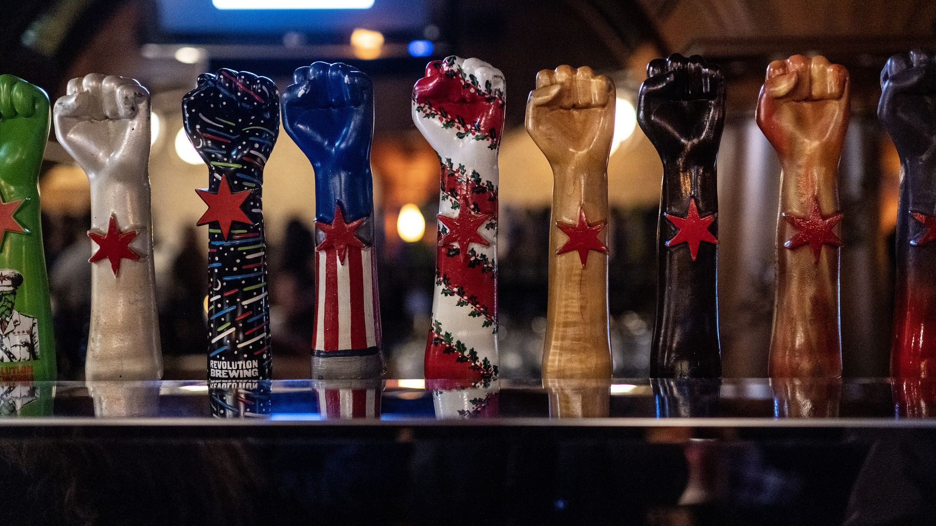 Beer taps shaped like an arm and fist but in different colors and designs with a red star in the center.
