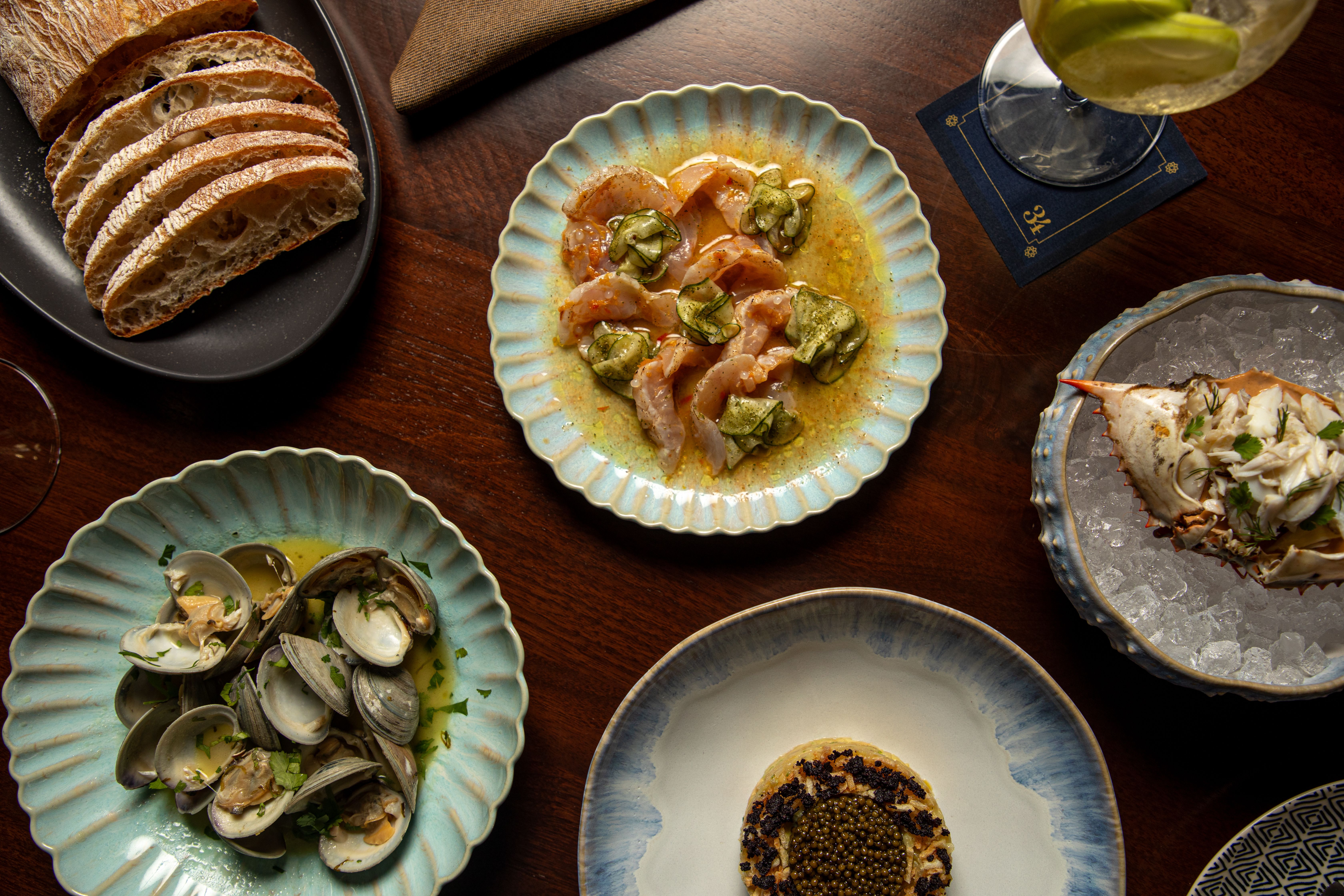 Several seafood dishes sit across a tabletop, viewed from above.