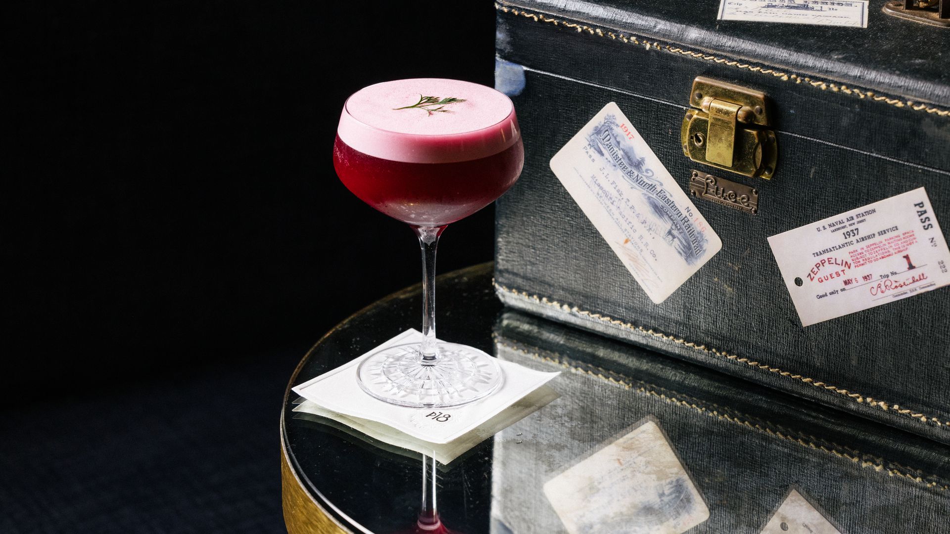 A cocktail next to an old-time suitcase.