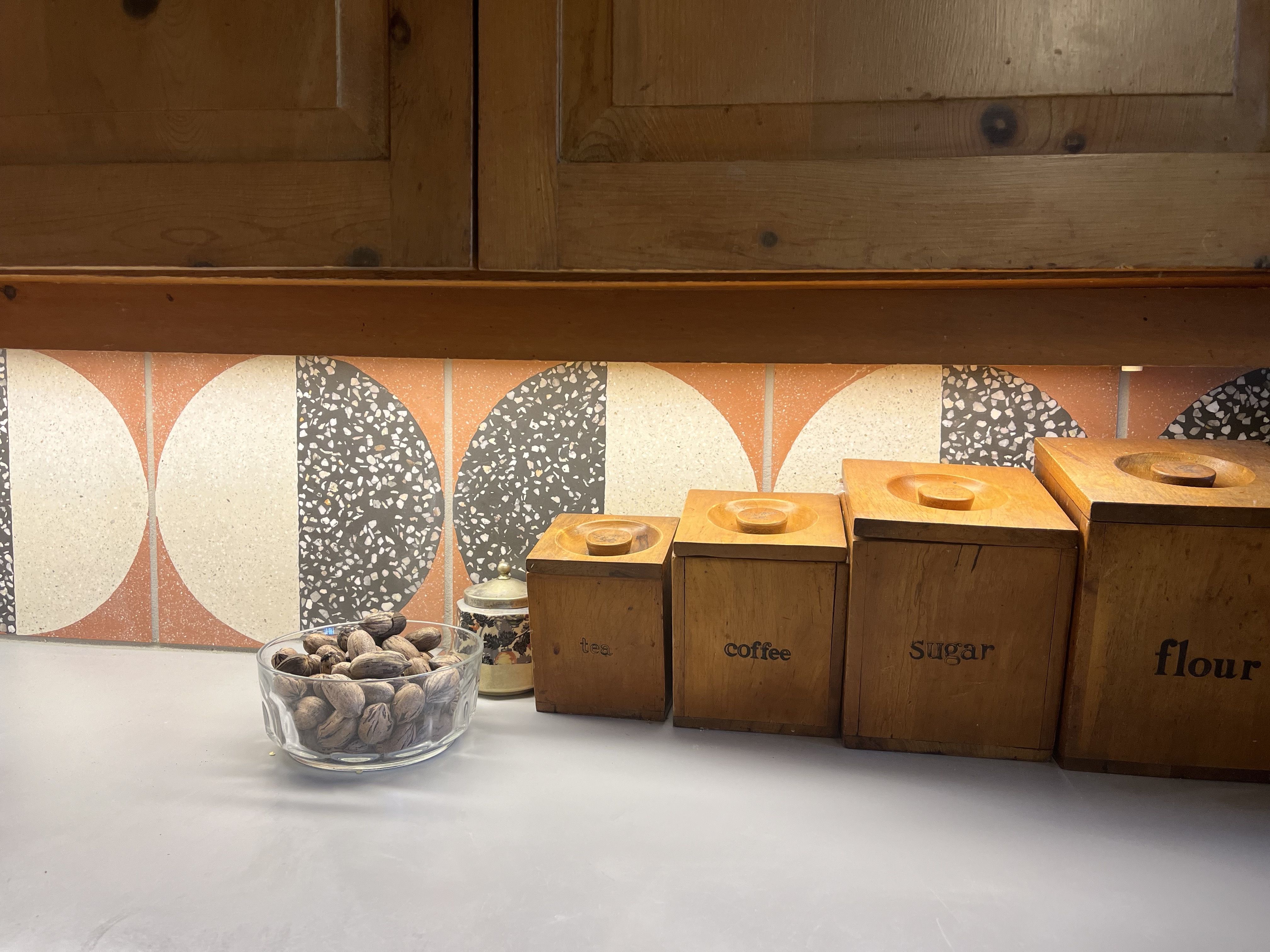 A kitchen counter with tiles and pecans.