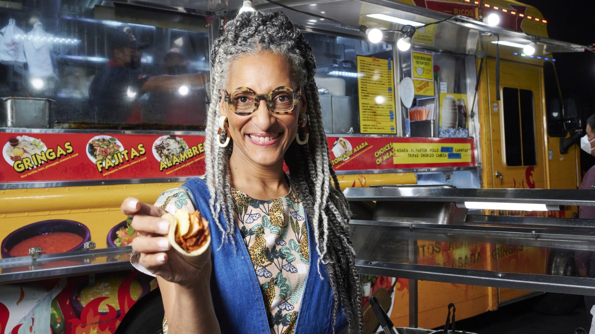 a woman holds a steamed bun infront of a food truck 