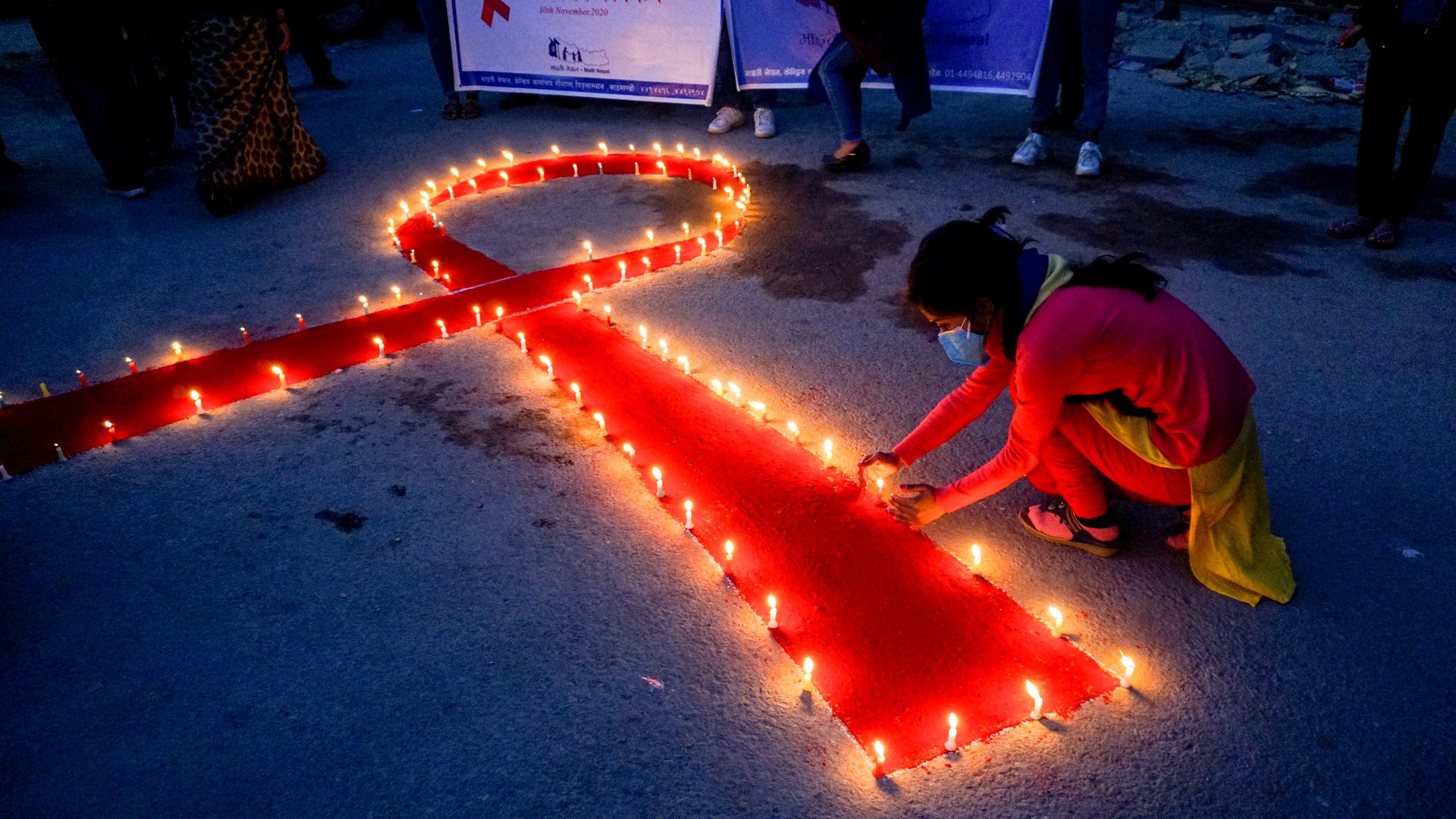  A woman lights candles forming a Red Ribbon (recognized symbol for AIDS awareness) as she prays for those who lost their lives due to HIV/Aids, on the eve of World AIDS Day