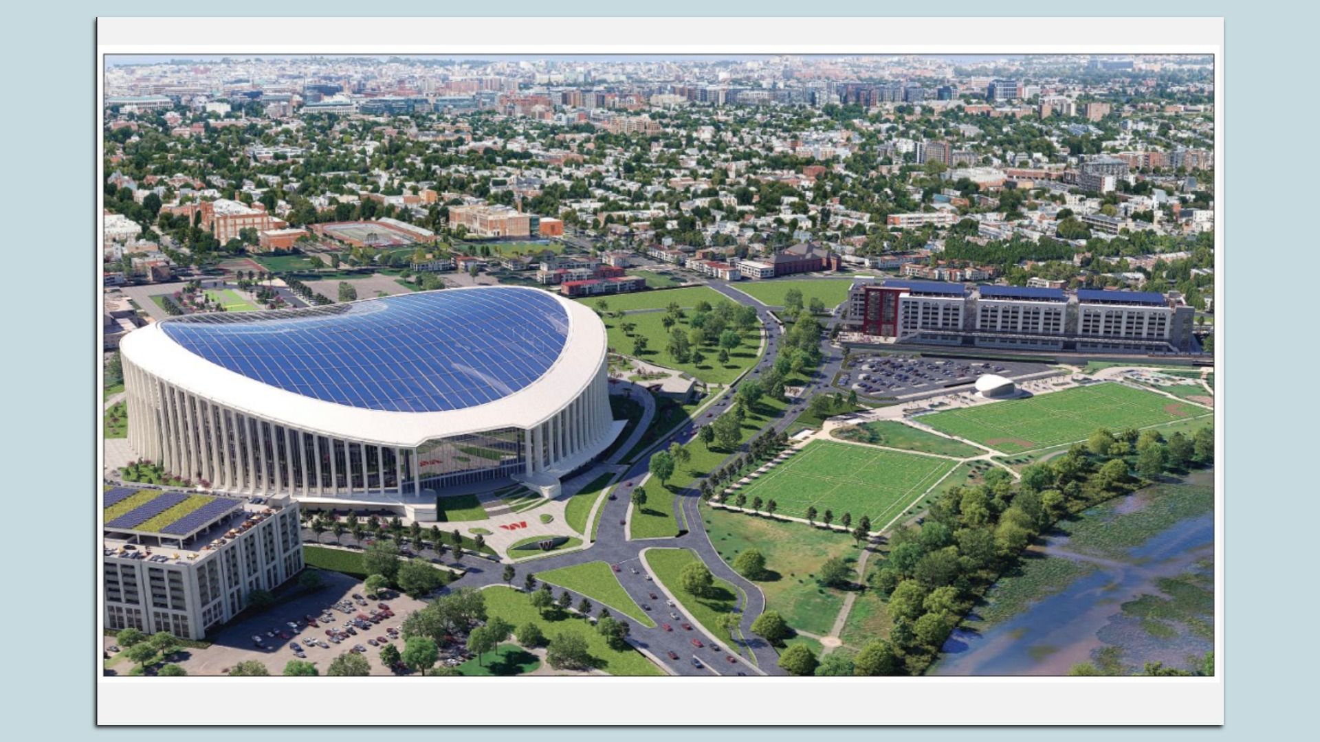 Aerial view of a city with a large curved white stadium with a blue roof in the foreground, surrounded by green parks, roads, and buildings, with a river along the right edge.