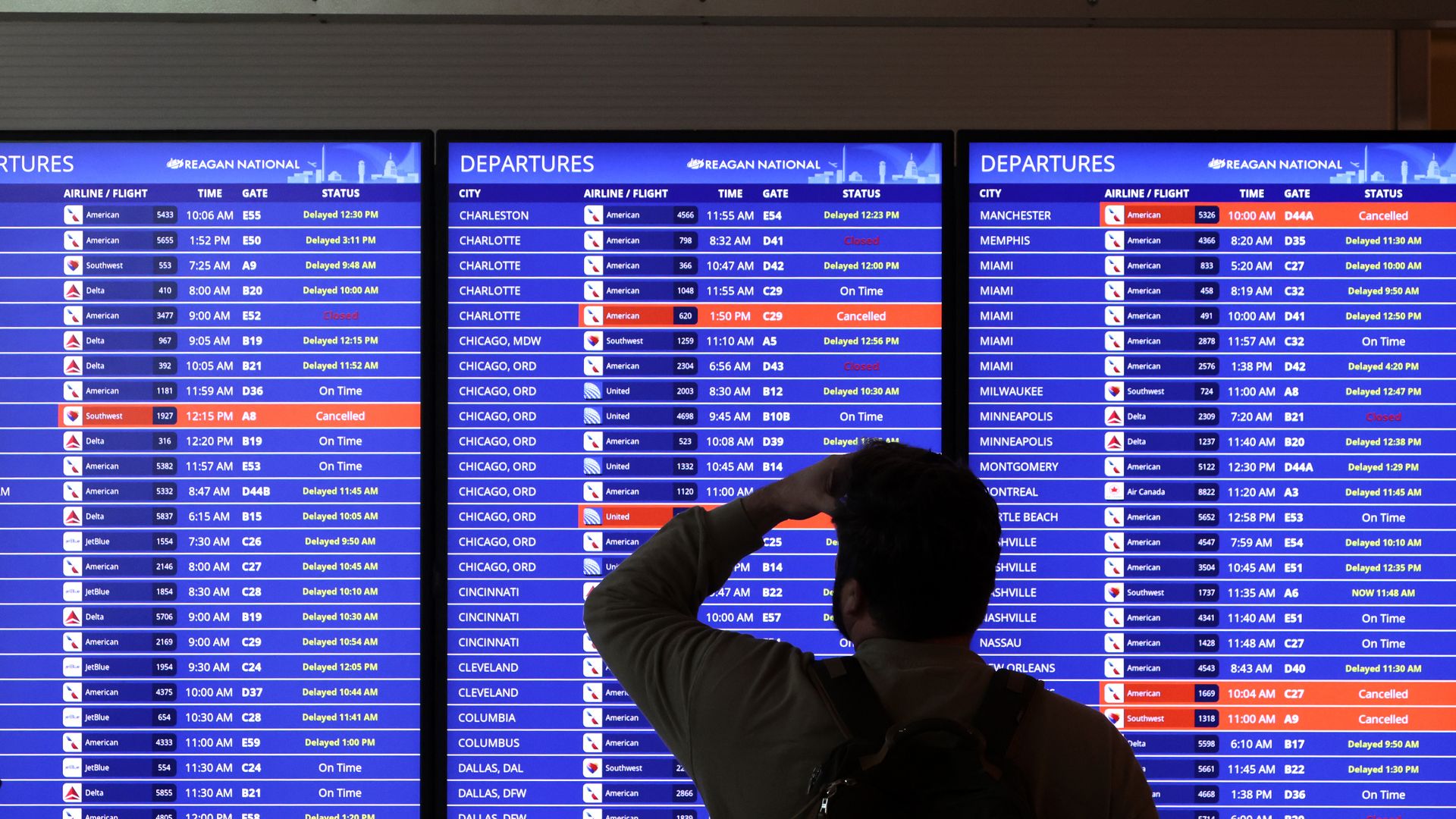 A traveler looks at a flight information board at Ronald Reagan Washington National Airport on Jan. 11, 2023.