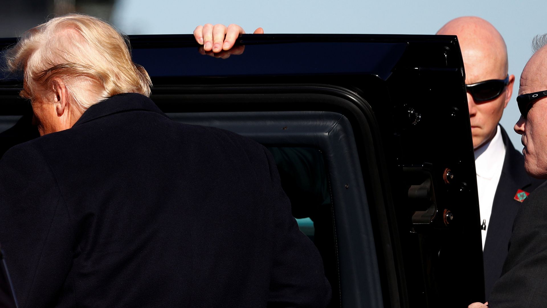In this image, the back of Trump's head is visible as he gets into a black armored car.
