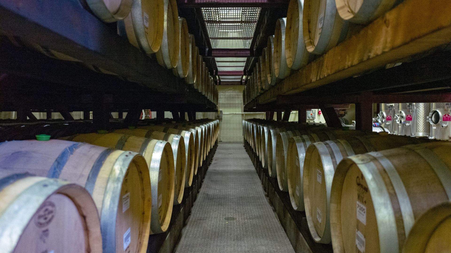 In this image, two rows of wine barrels are stacked on top of each other. 