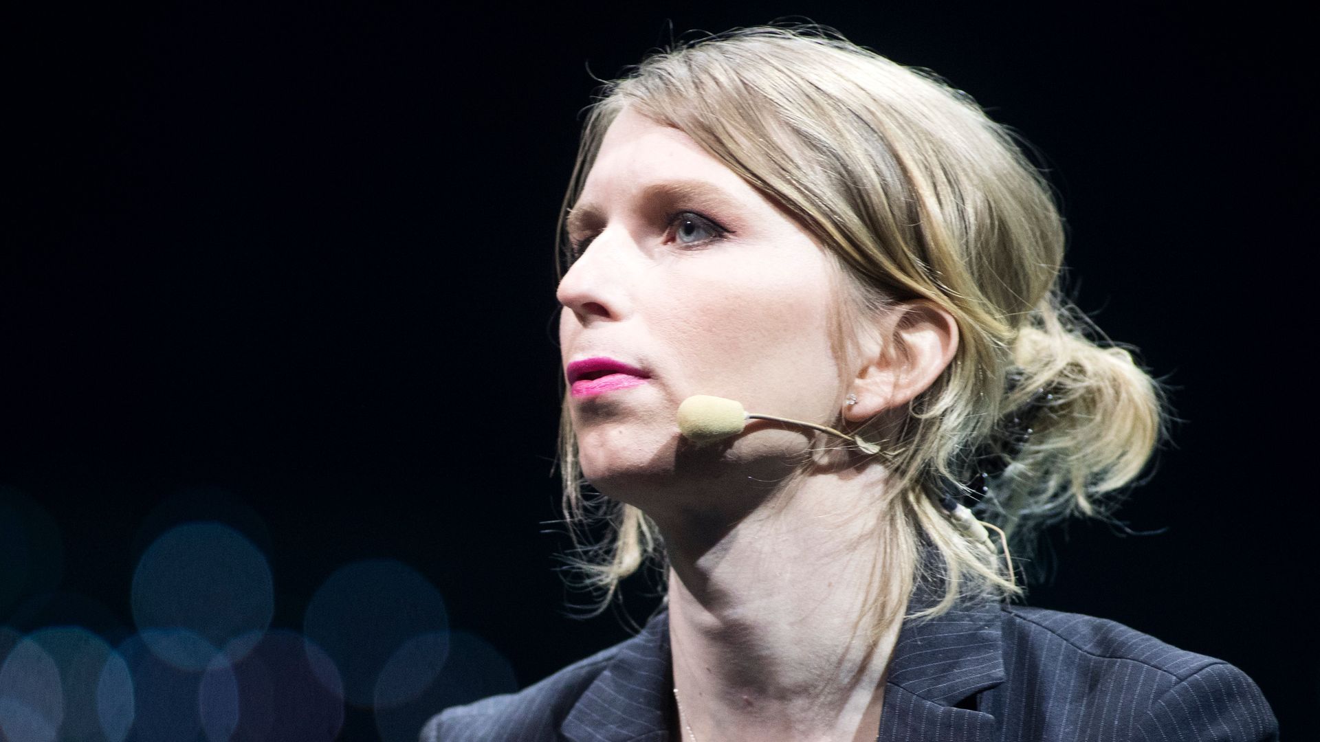 In this image, Chelsea Manning looks to the left while wearing a microphone. 