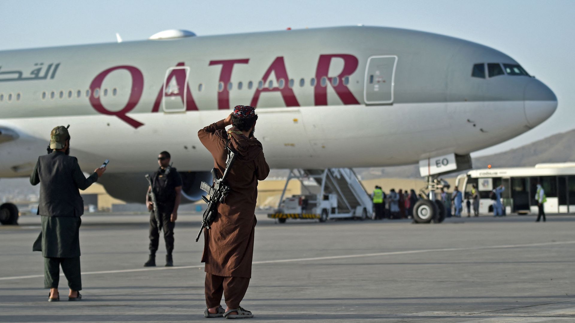 Taliban fighter standing next to Qatar Airways flight