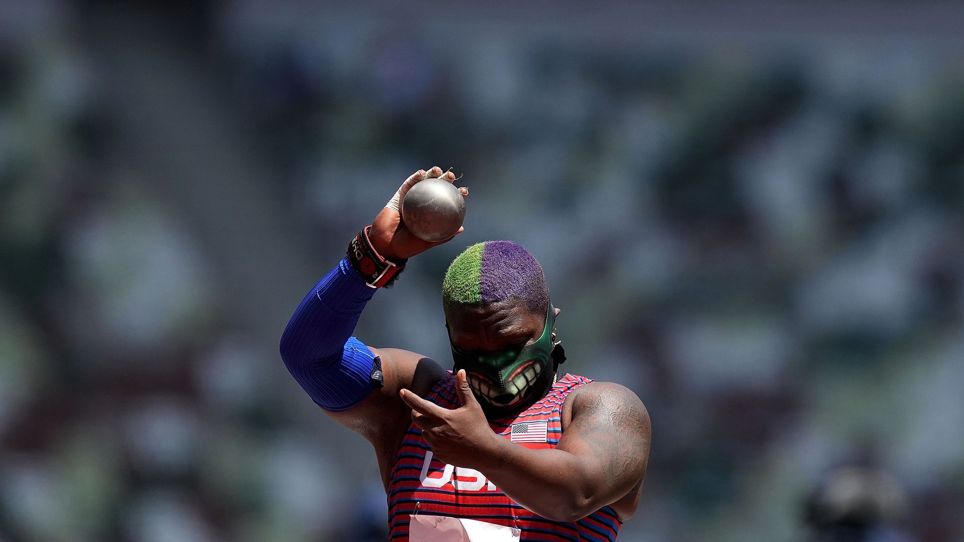 Photo of an athlete holding up a shot put