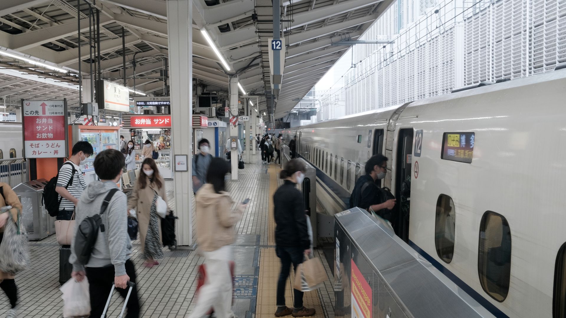 Passengers wearing protective masks board an East Japan Railway Co. (JR East) Shinkansen bullet train