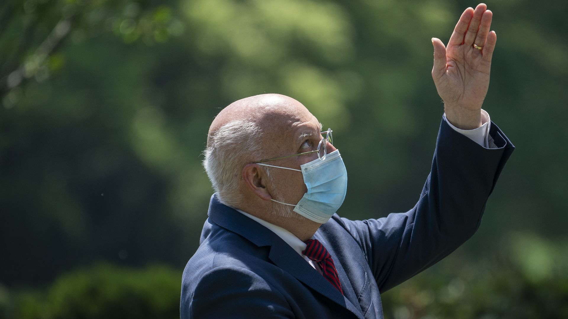 Robert Redfield wears a mask and points at the sky