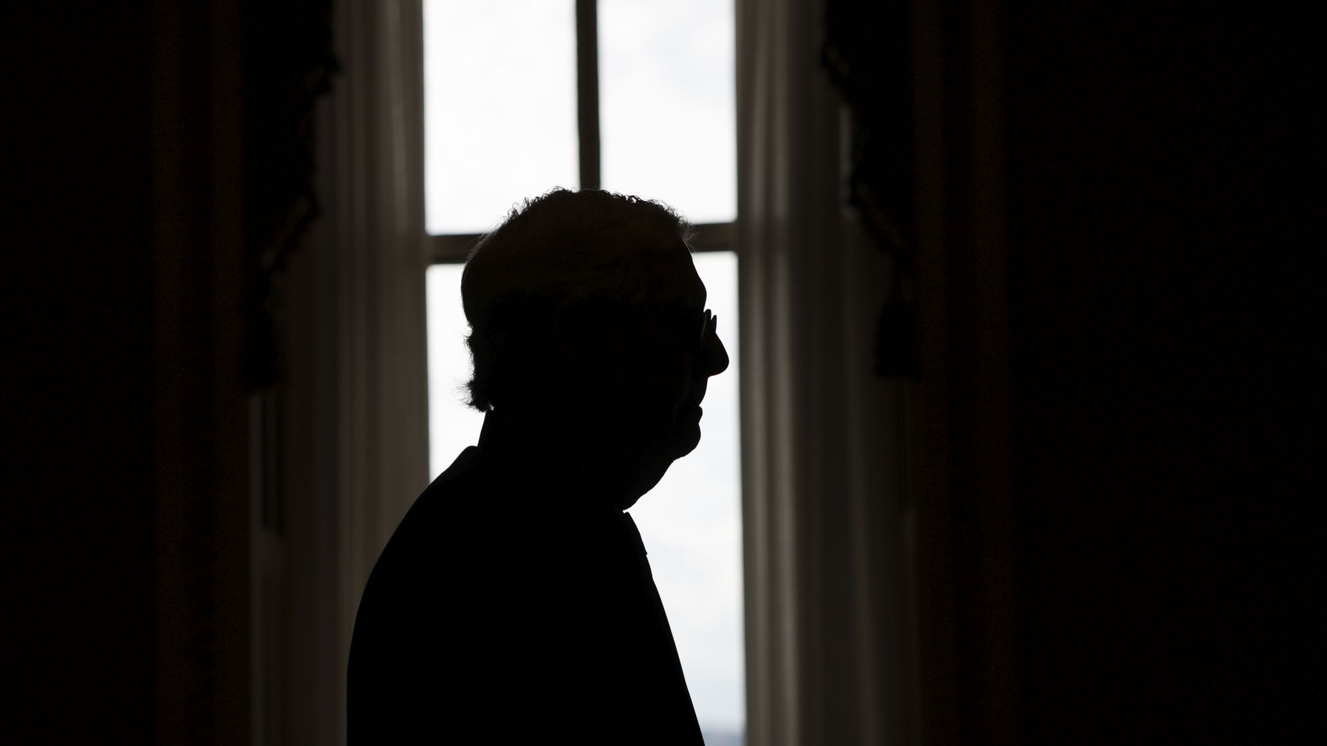 Senate Minority Leader Mitch McConnell is seen in silhouette as he walks through the Capitol.