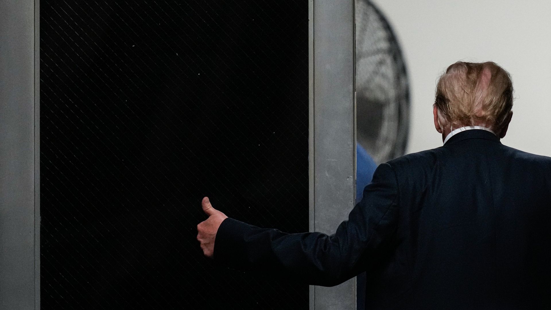 Photo of Trump from behind with thumb up