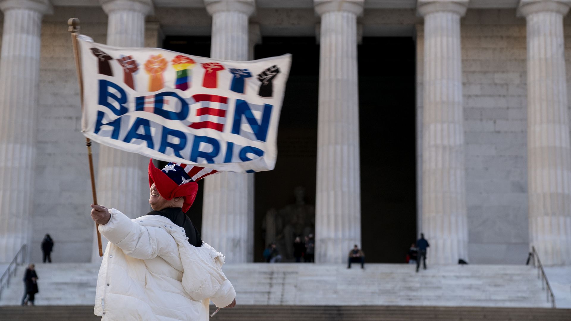A reveler is seen with a Biden-Harris banner in front of the Lincoln Memorial.
