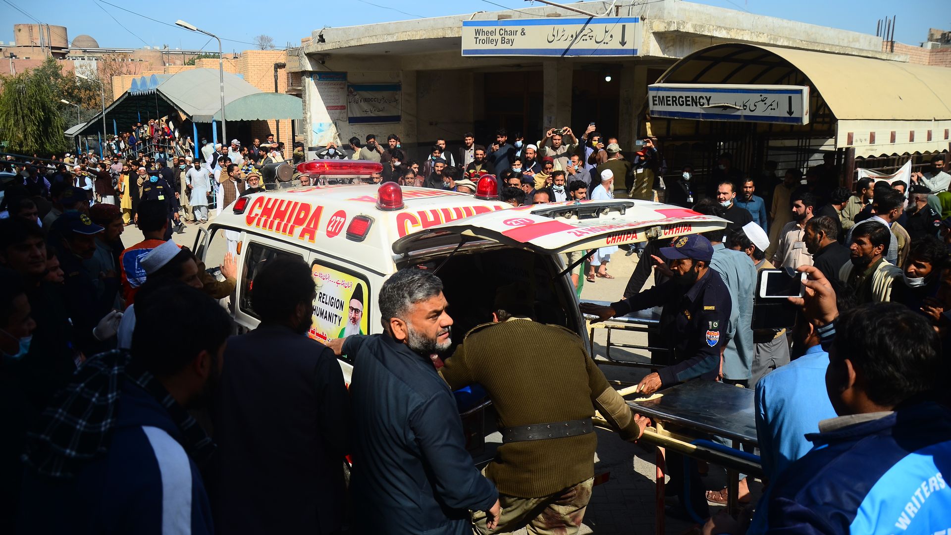 People carry an injured person to an abulance after a suicide bomber blew himself up during weekly Friday prayers at a Shia mosque in northwestern Pakistan