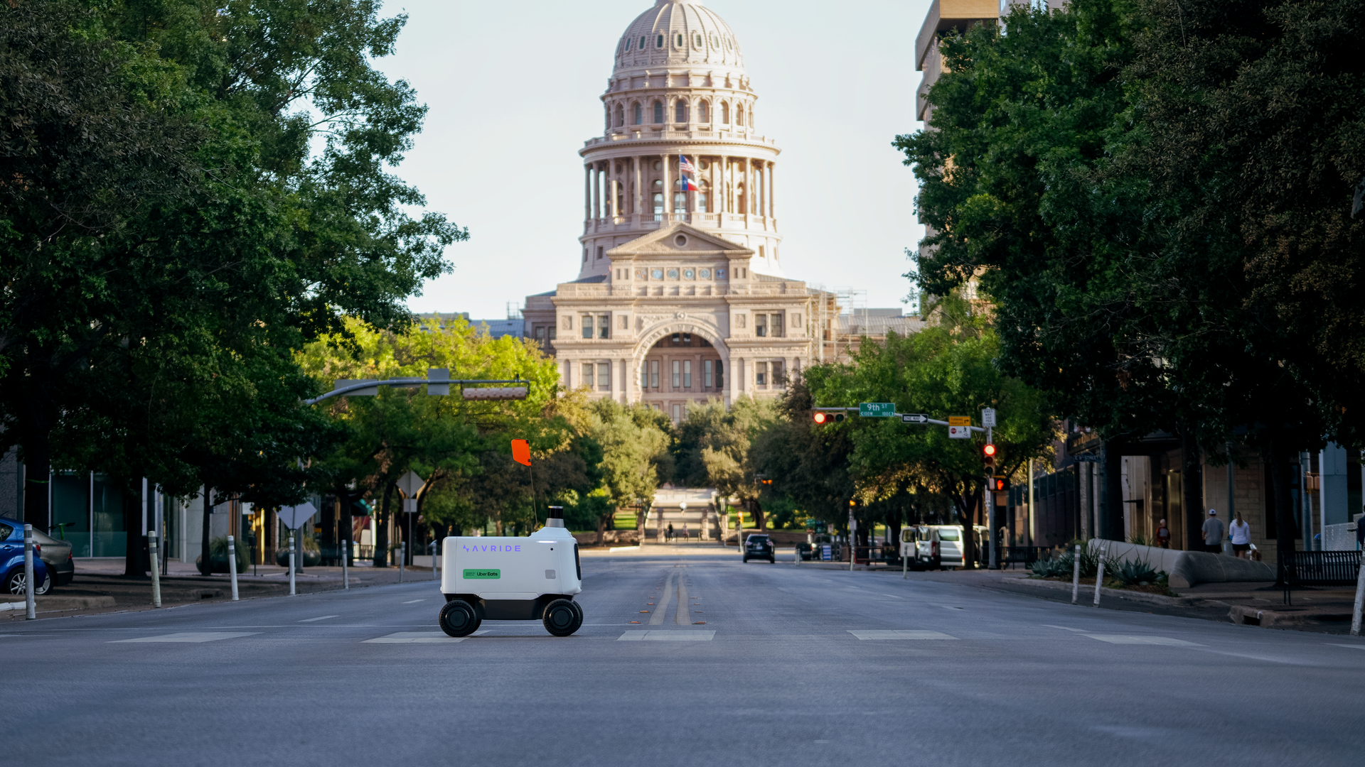 A delivery robot crosses the street in front of the Texas Capitol.