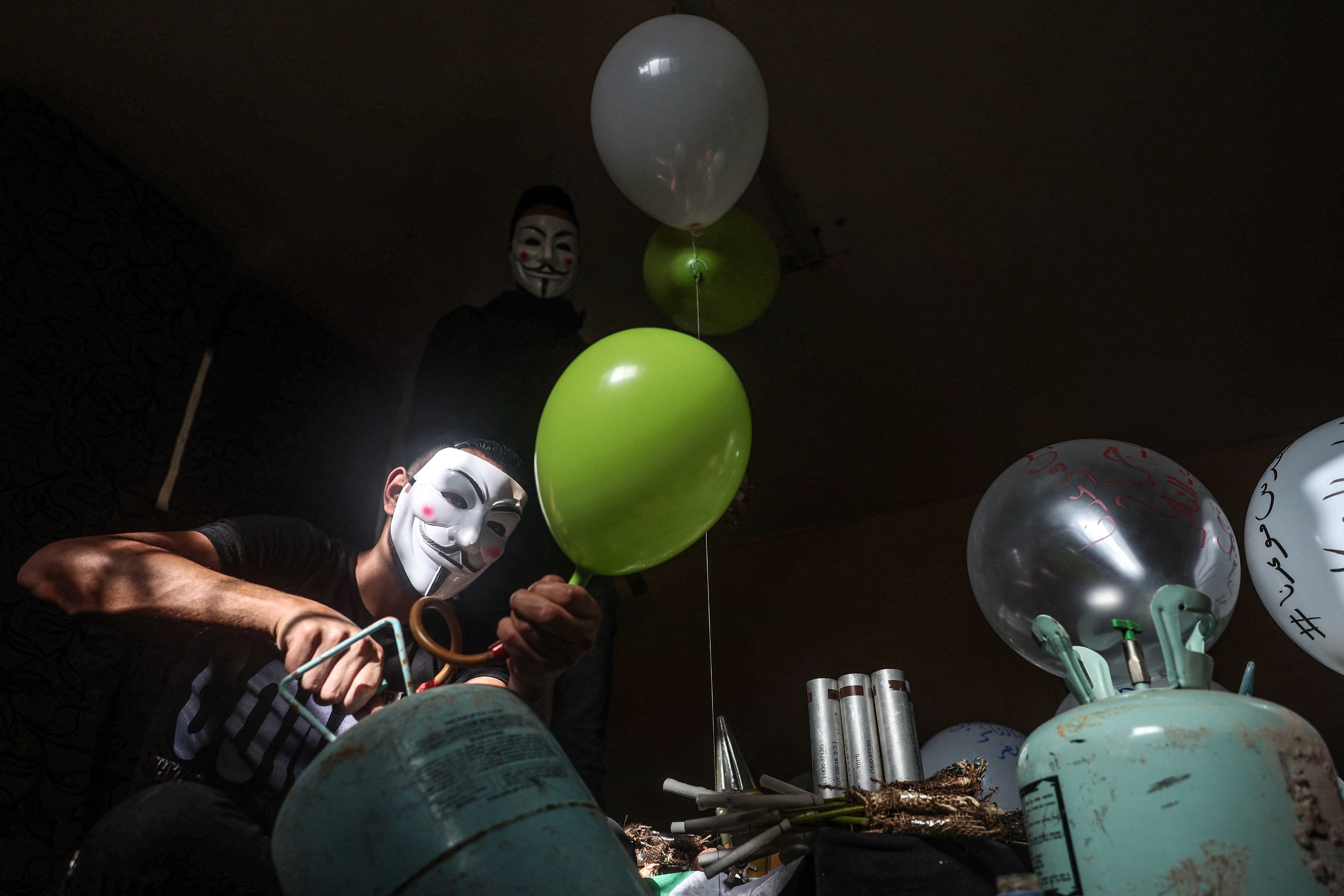 Masked Palestinian followers of the Hamas movement prepare incendiary balloons with anti-Israel slogans written on them, near Beit Lahia in the Gaza Strip