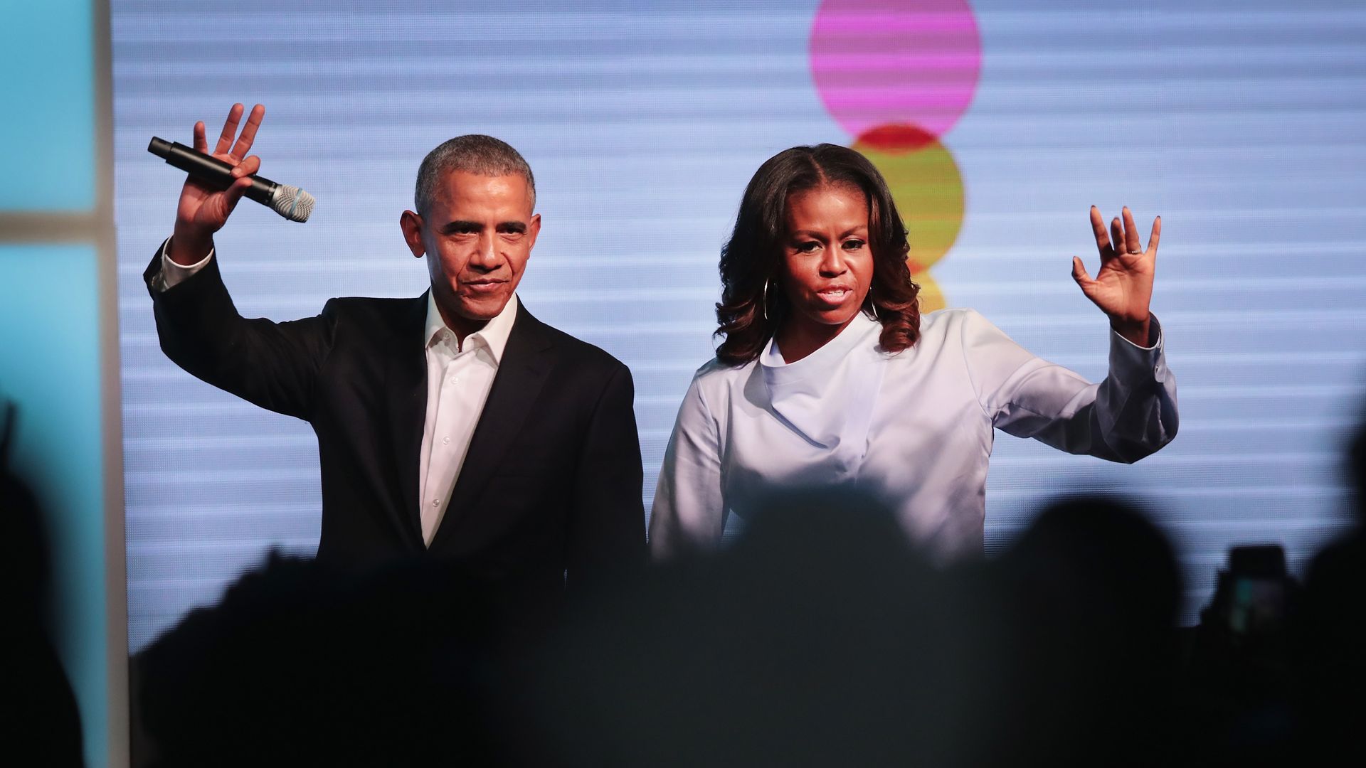 Photo of the Obamas holding hands and waving to a crowd