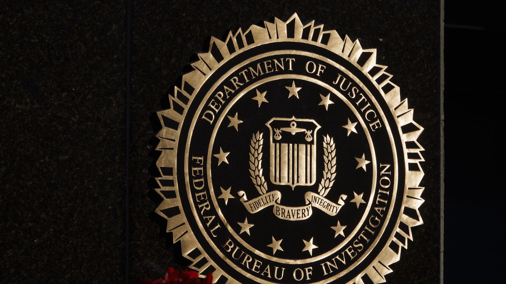 A gold, round seal of the Federal Bureau of Investigation can be seen on a building's wall.