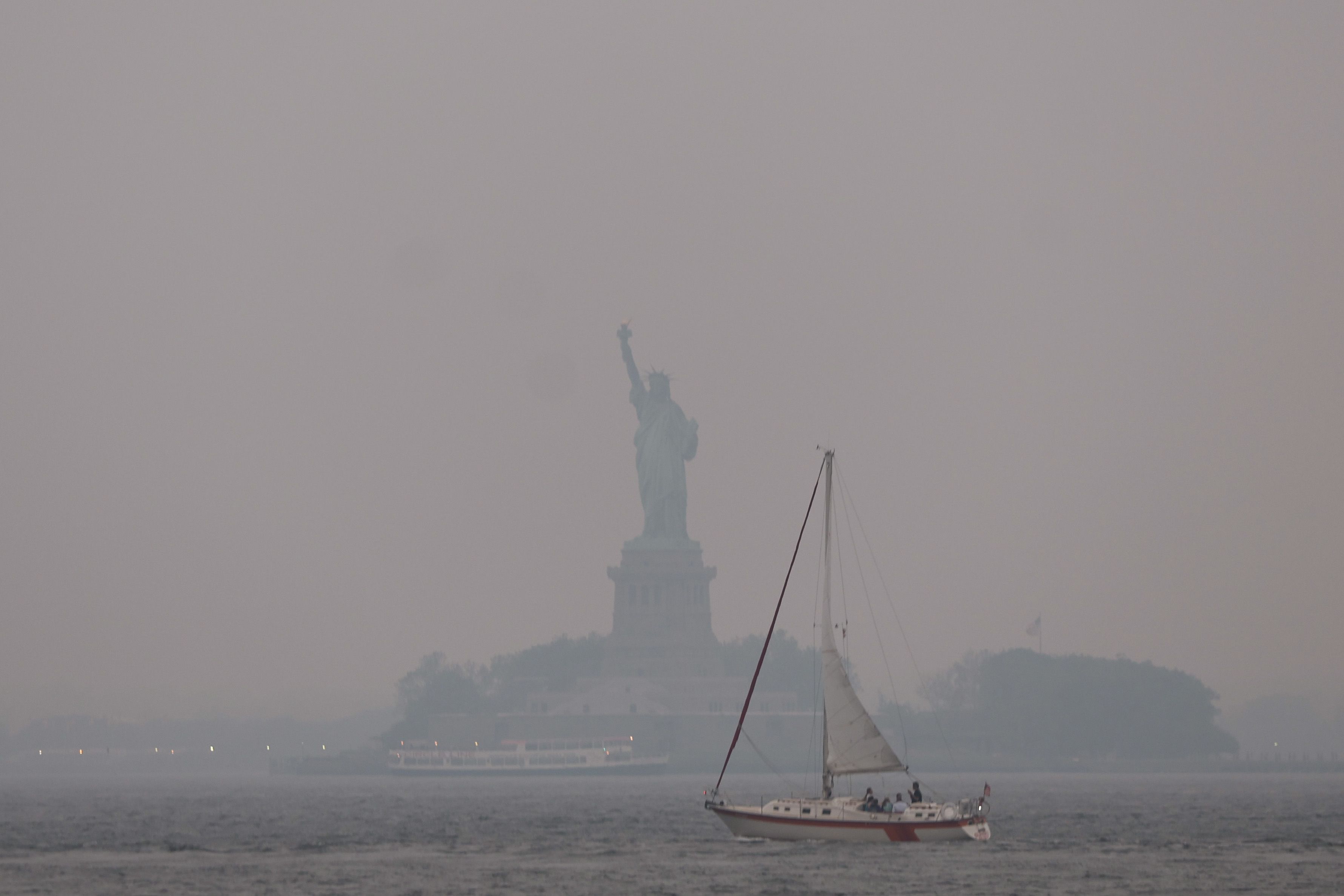 The Statue of Liberty stands shrouded in a reddish haze as a result of Canadian wildfires on June 06, 2023 in New York City. 