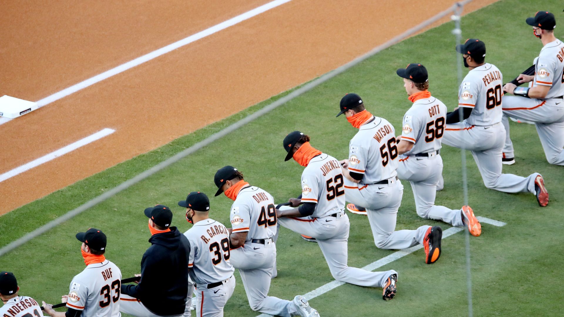 The San Francisco Giants kneel and hold a black ribbon to show their support for social justice and diversity and inclusion in baseball and life during the pre-game ceremony prior to the game the game between the Giants and the Los Angeles Dodgers at Dodger Stadium on July 23, 2020.