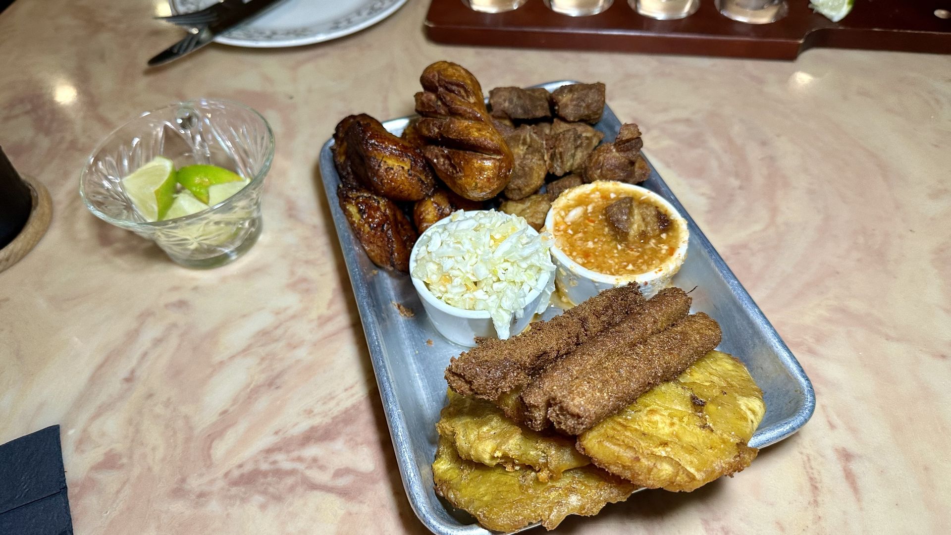 Photo shows various Haitian dishes on a metal tray.