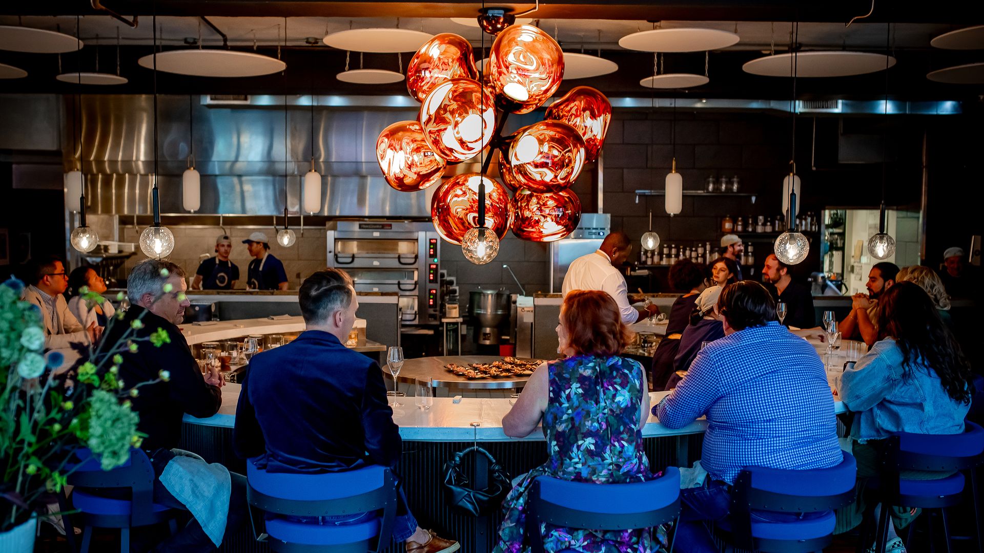 One by Spork diners at the circular chef's counter below a red Melt Burst chandelier in Pittsburgh
