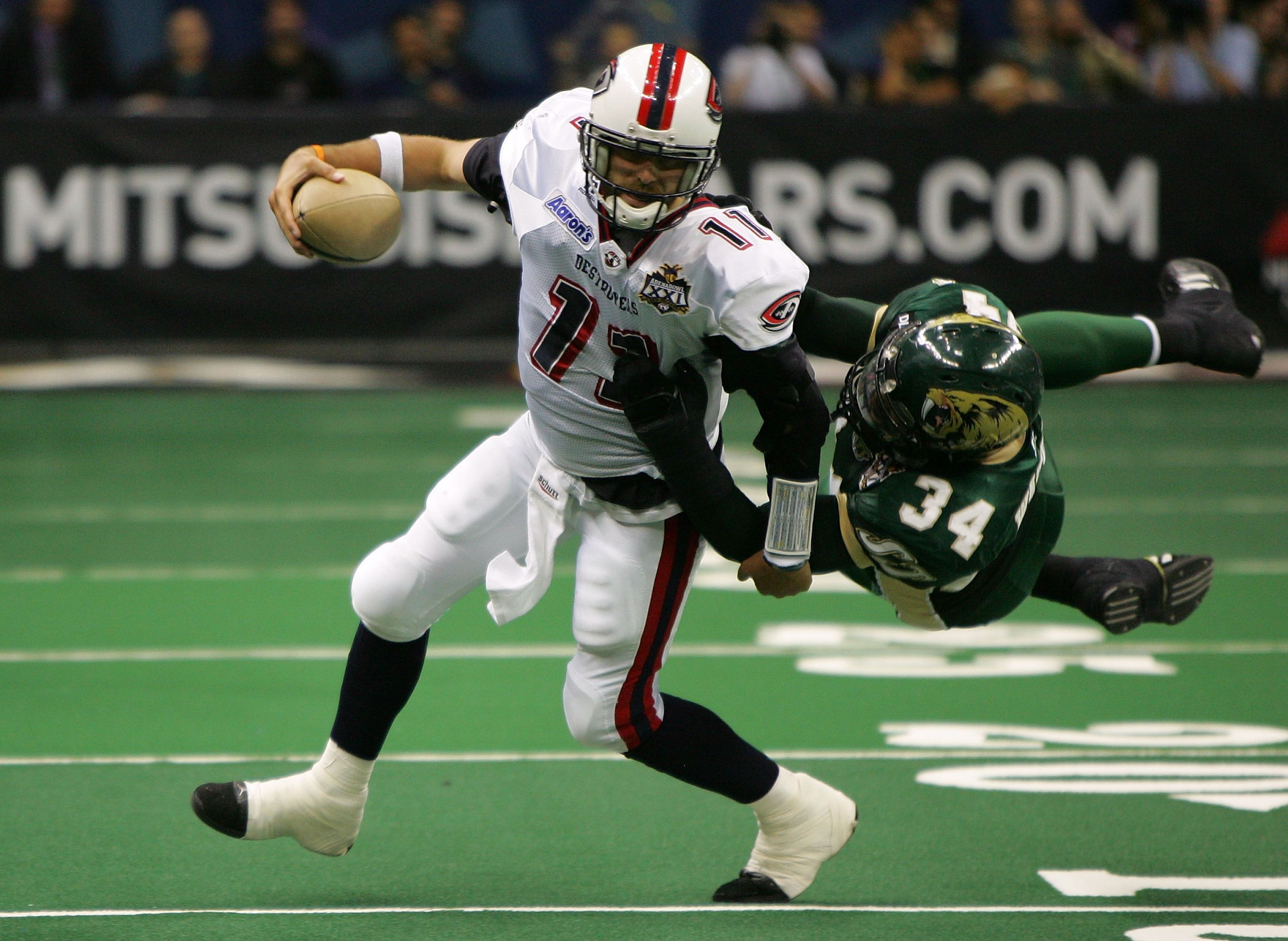 Arena football player Matt Nagy runs with the football as an opposing player dives to tackle him. 