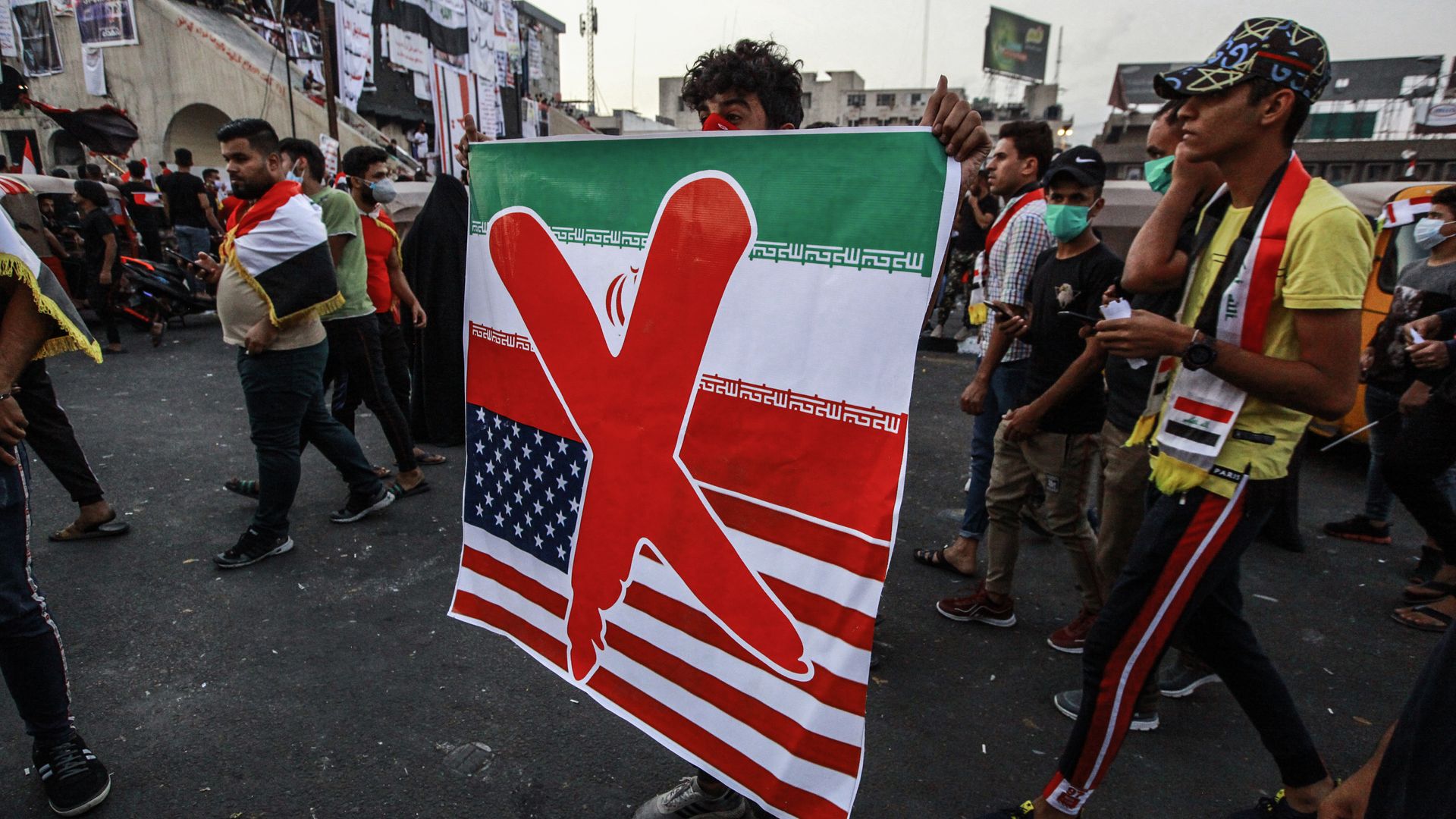 Protestor in Baghdad with sign showing big X across U.S. and Iranian flags