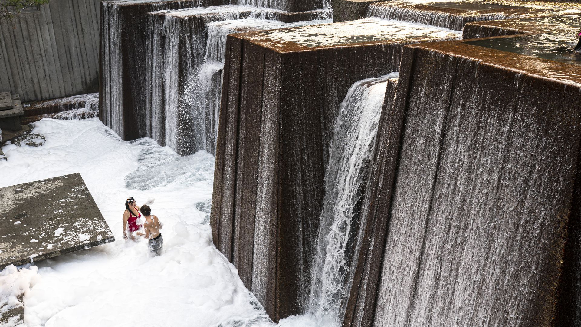 Portland residents stay cool in a public fountain filled with soap suds during a heatwave.