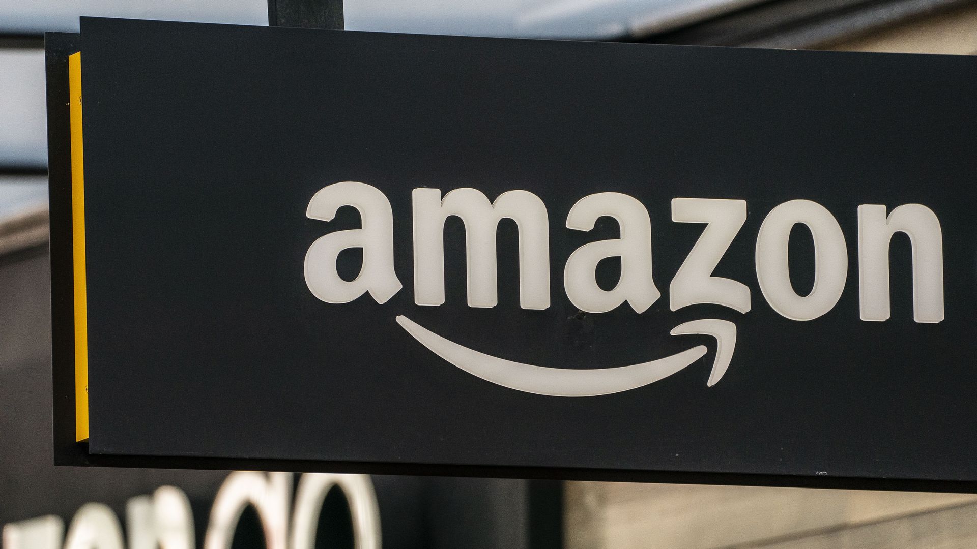 Photo of a sign that shows the Amazon logo hanging from a building