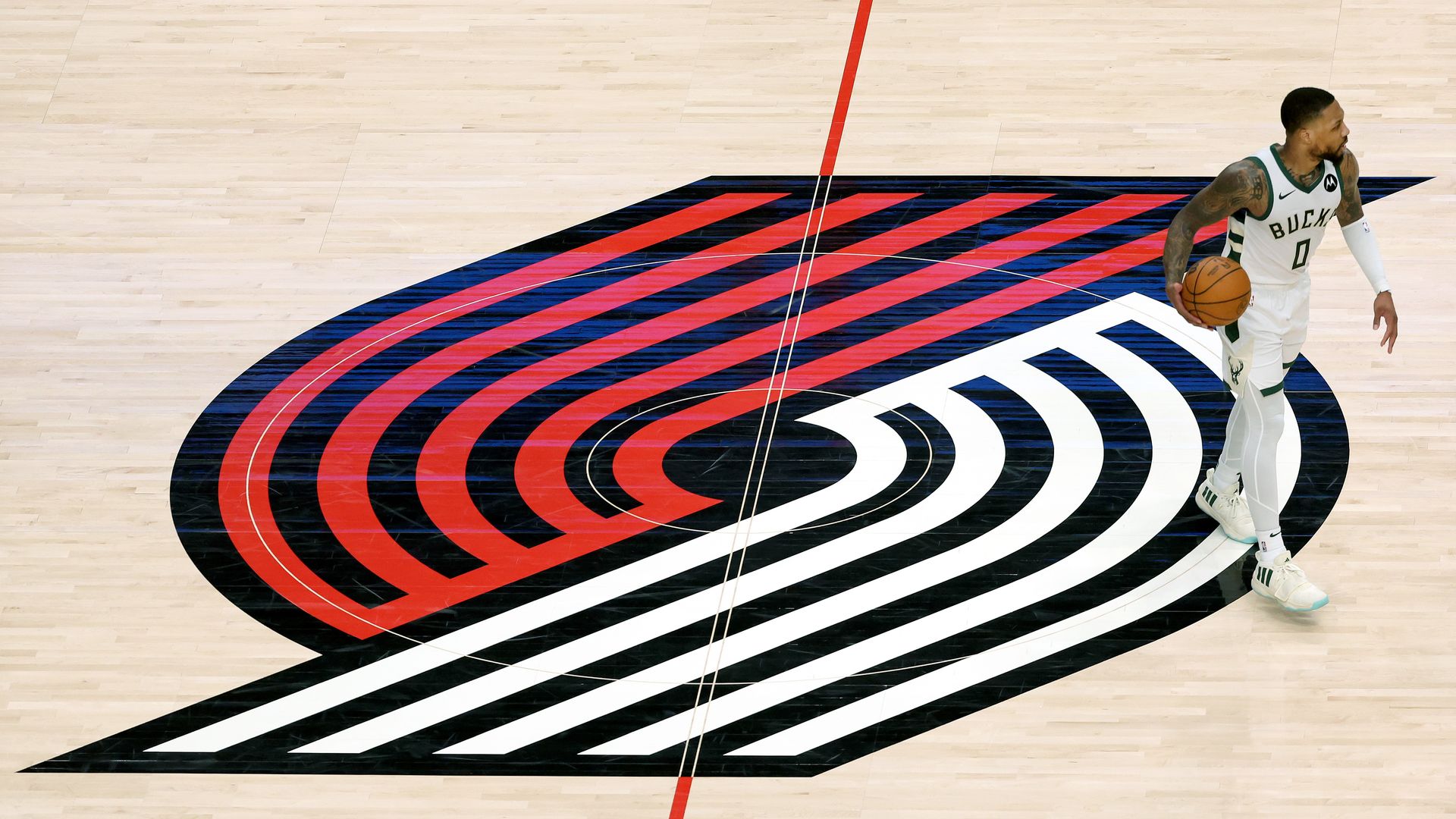 A photo of a person walking and dribbling a basketball next to a Portland Trail Blazers logo.