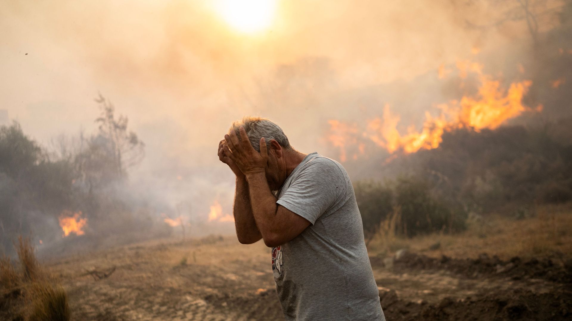 A man reacts as a fire burns into the village of Gennadi on the Greek Aegean island of Rhodes, on July 25, 2023. Wildfires have been raging in Greece amid scorching temperatures, forcing mass evacuations in several tourist spots including on the islands of Rhodes and Corfu.